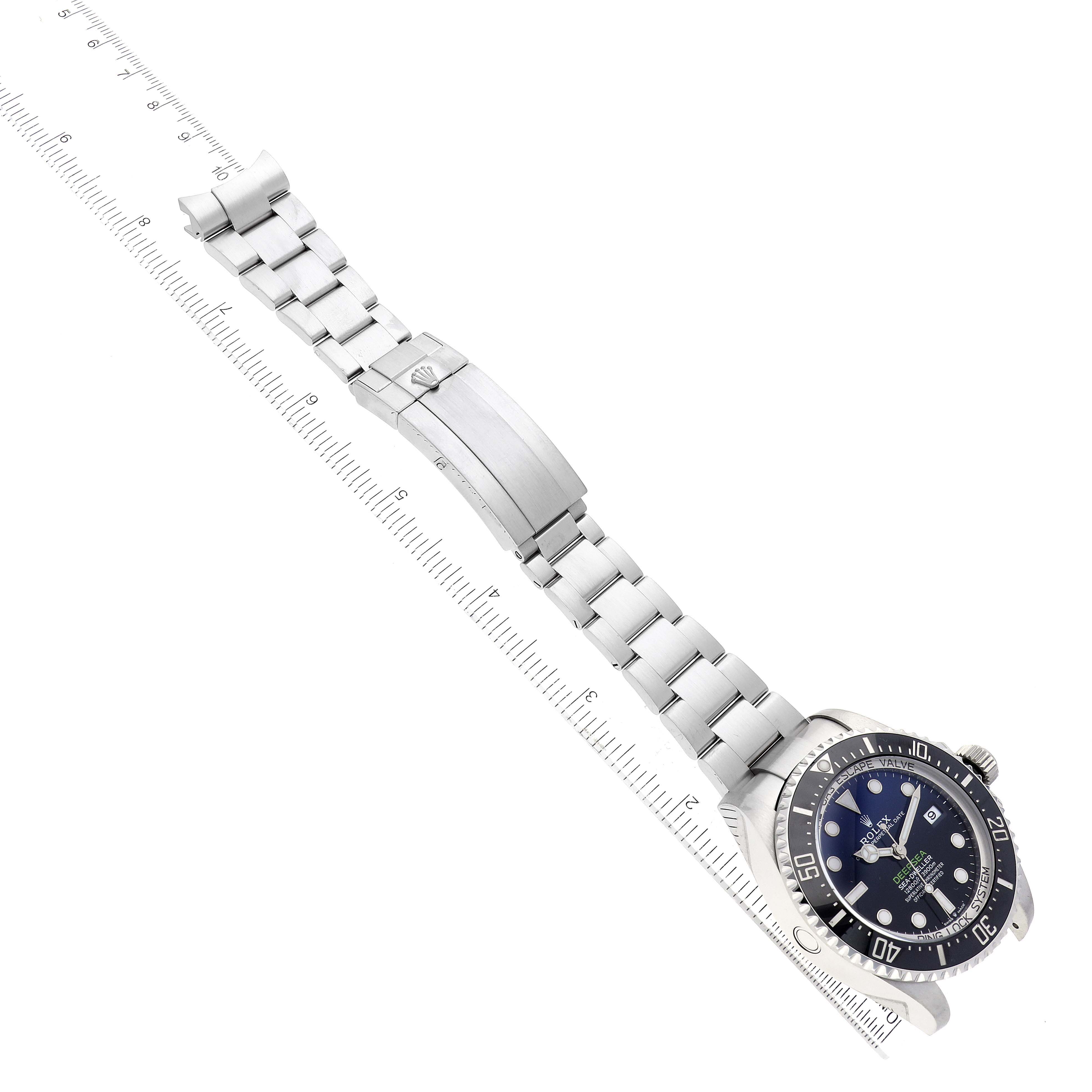 The image showcases a Rolex Sea-Dweller 136660 Men
s Stainless Steel Blue Dial 136660 Men
s Stainless Steel Blue Dial watch laid flat, displaying the dial, case, bezel, and full metal bracelet with clasp.