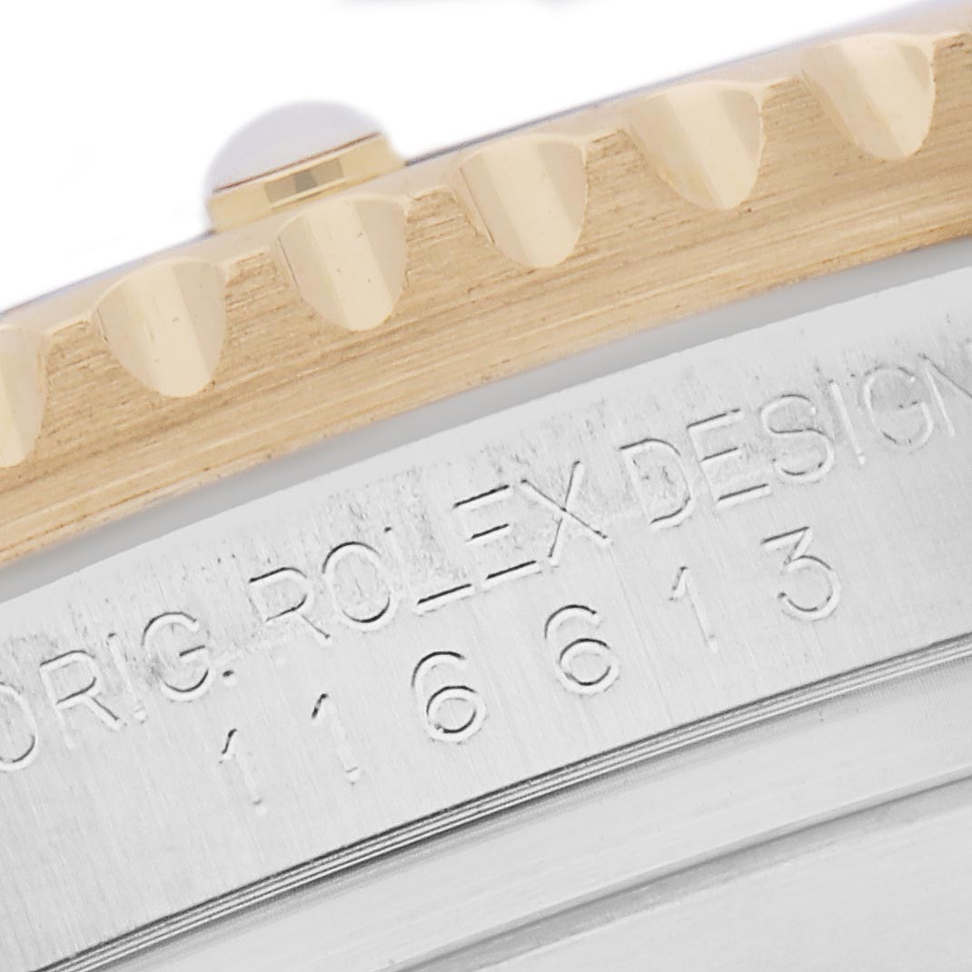 The image shows a close-up of the Rolex Submariner 116613 Men
s Steel and Gold (two tone) Black Dial 116613 Men
s Steel and Gold (two tone) Black Dial
s bezel edge and case side, featuring engraved text and model number.