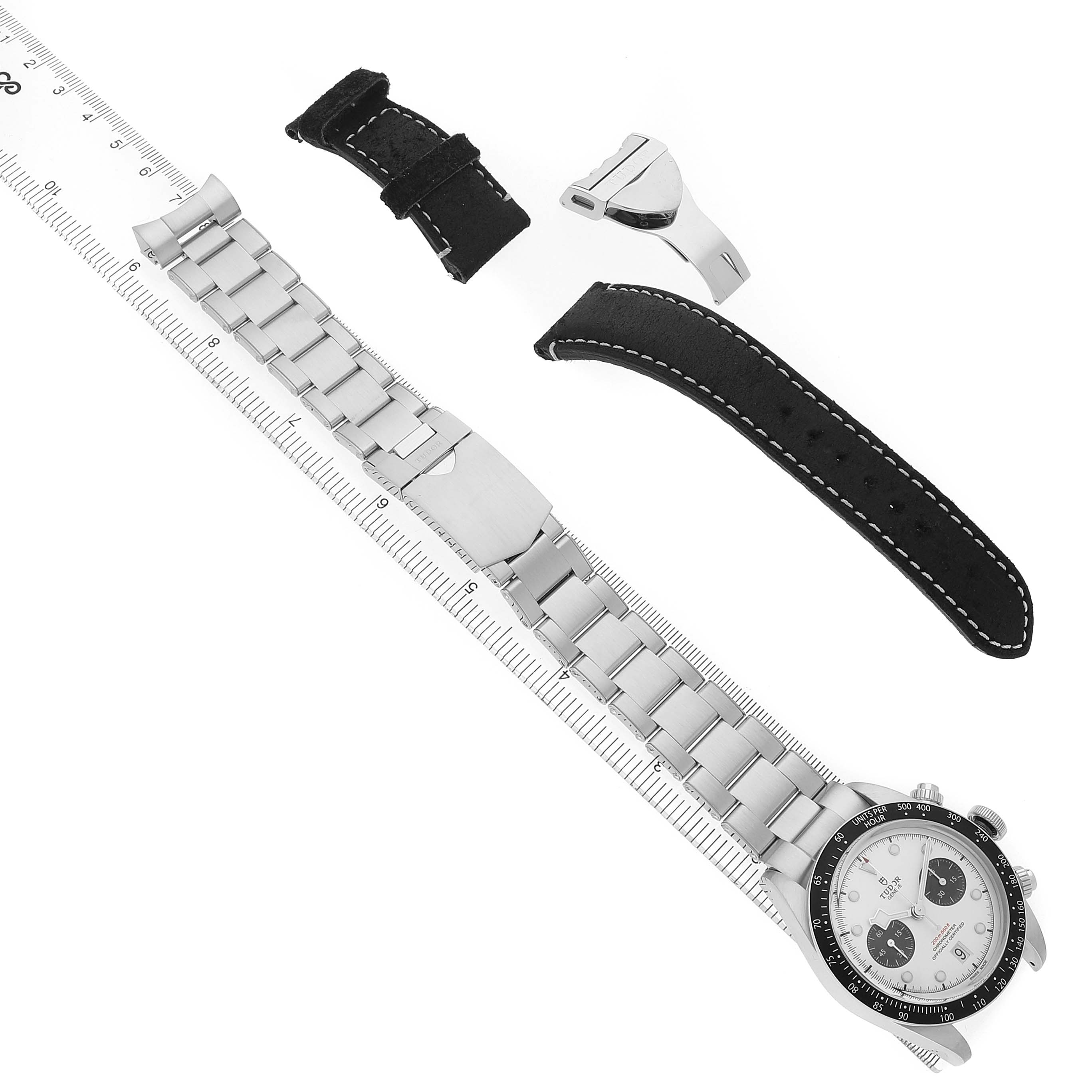 The Tudor Heritage Black Bay 79360 Men's Stainless Steel Silver Dial watch is shown from a top view, with its metal bracelet, clasp, and additional leather strap parts displayed.