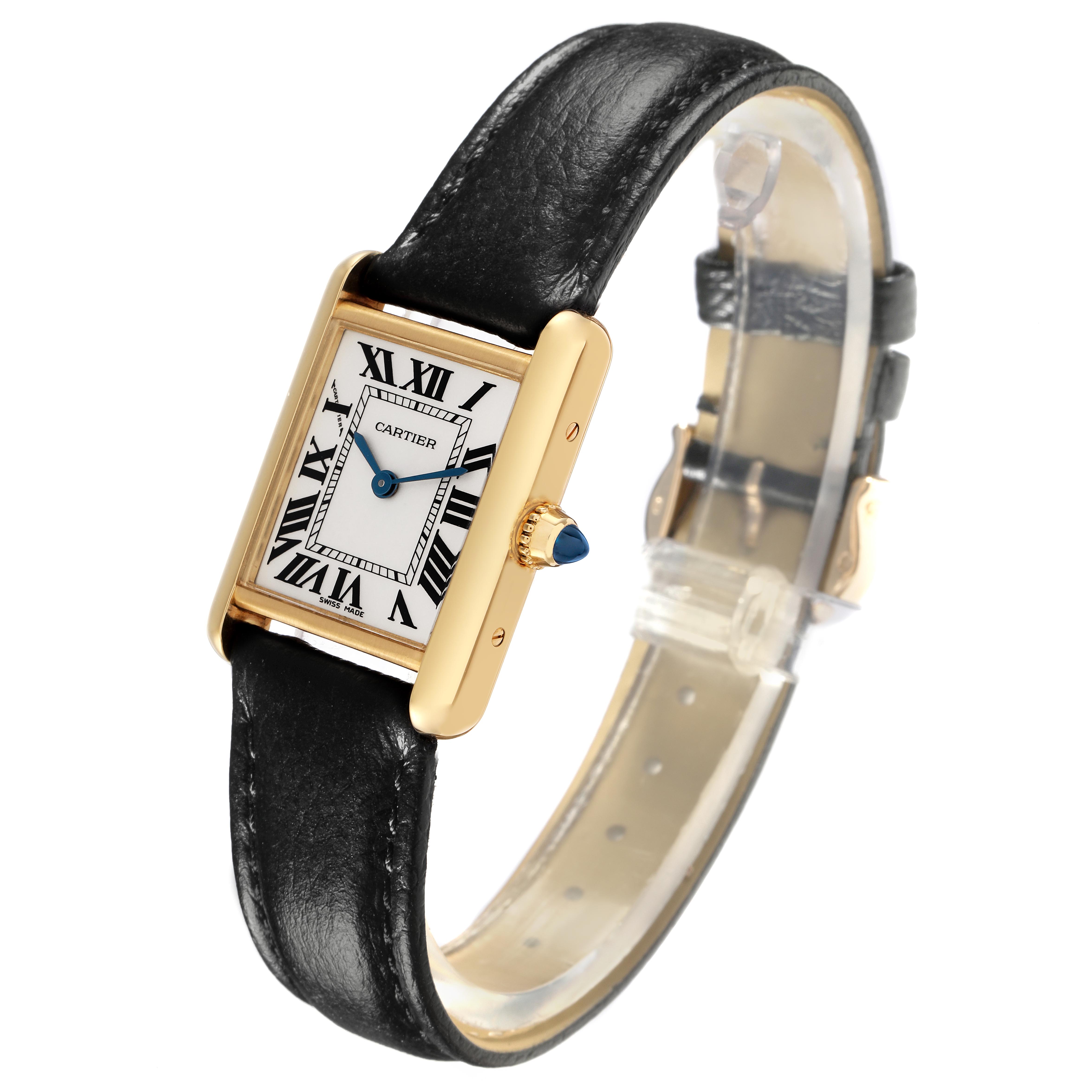 The Cartier Tank Louis W1529856 Women
s Yellow Gold White Dial W1529856 Women
s Yellow Gold White Dial watch is shown at a dynamic angle, highlighting its rectangular face, black leather strap, and gold casing.