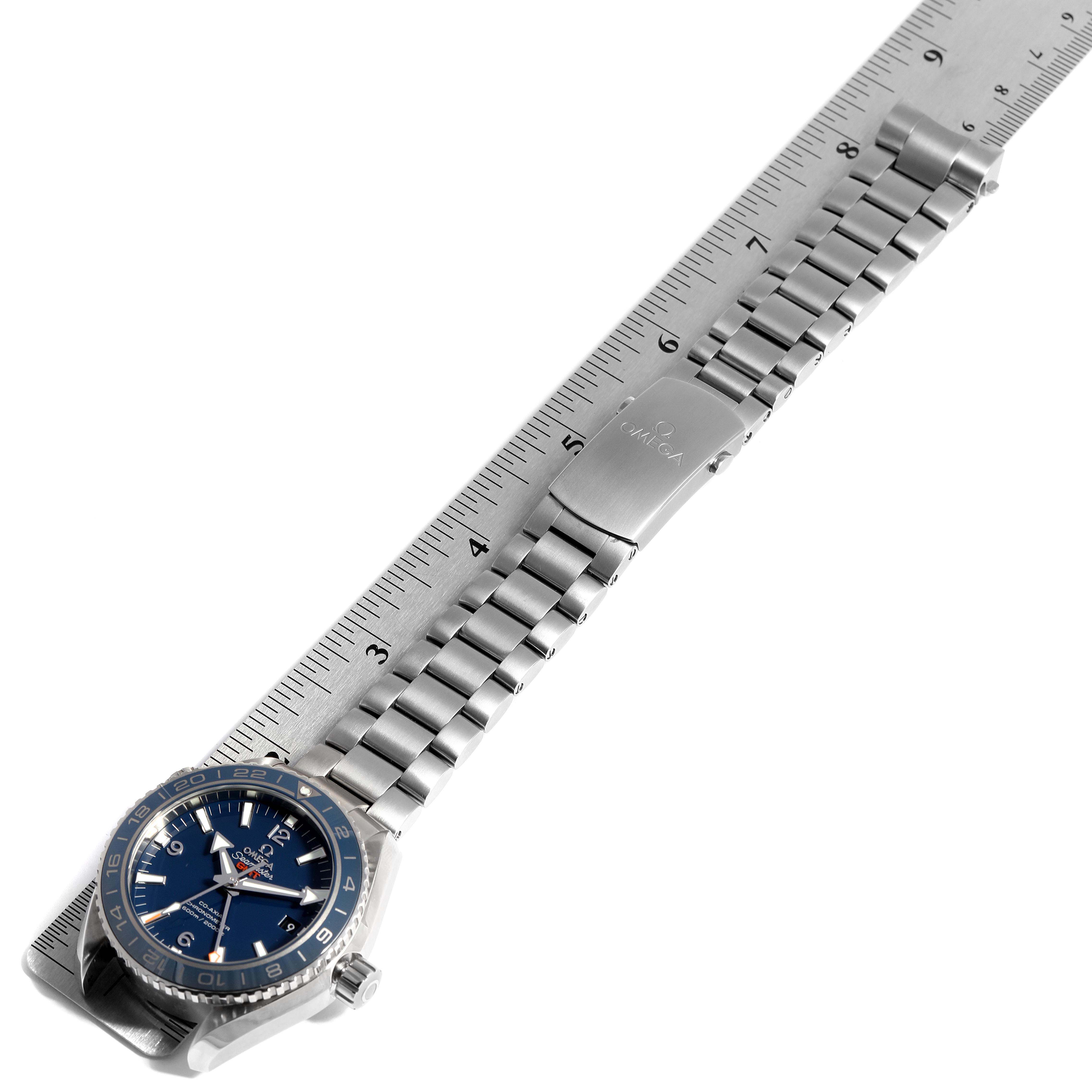 The image shows an Omega Planet Ocean 232.90.44.22.03.001 Men's Titanium Blue Dial 232.90.44.22.03.001 Men's Titanium Blue Dial watch with a blue dial and stainless steel bracelet against a ruler, displaying its length.
