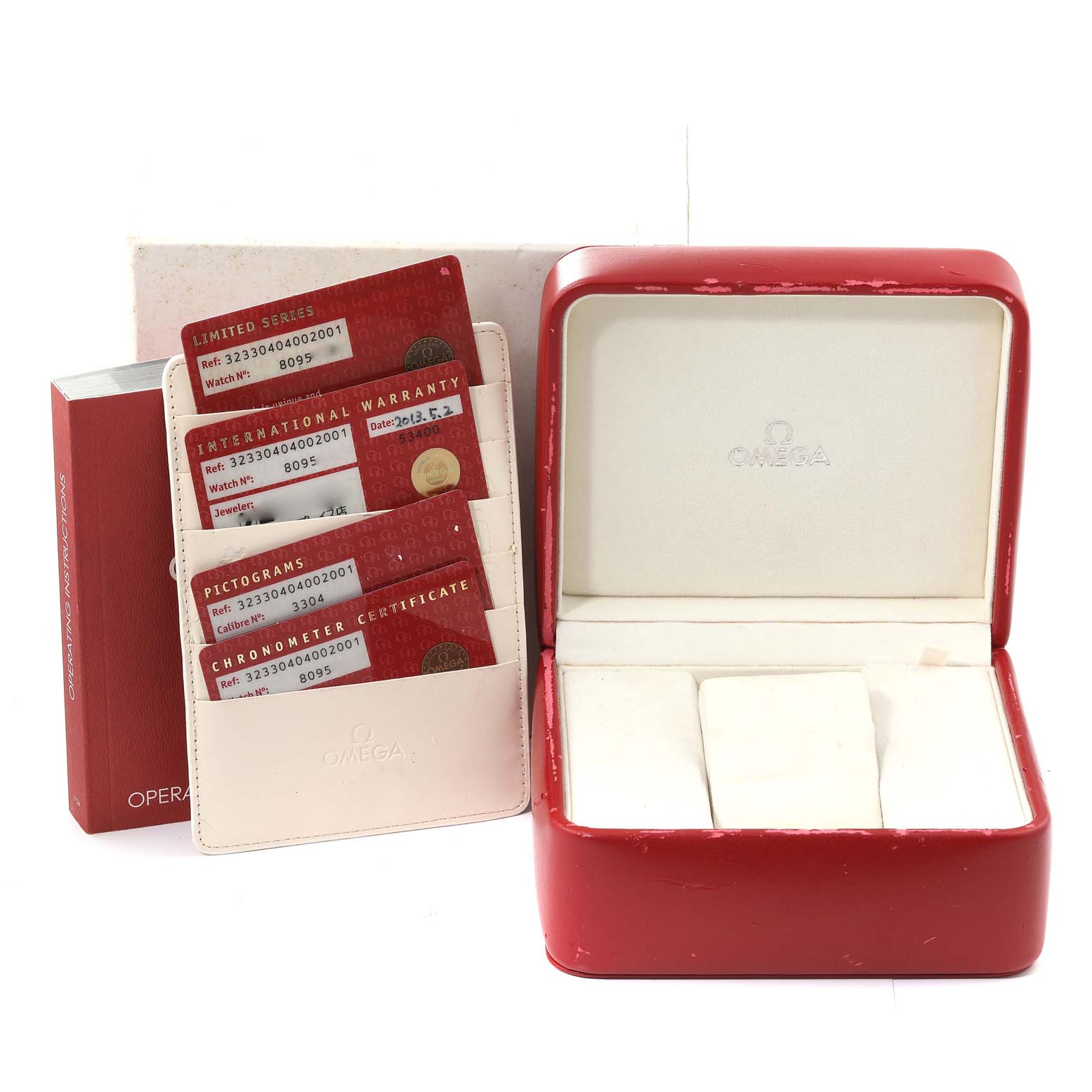 The image shows an open Omega Speedmaster 323.30.40.40.02.001 Men
s Stainless Steel White Dial 323.30.40.40.02.001 Men
s Stainless Steel White Dial watch box, warranty cards, a certificate holder, and an instruction manual.