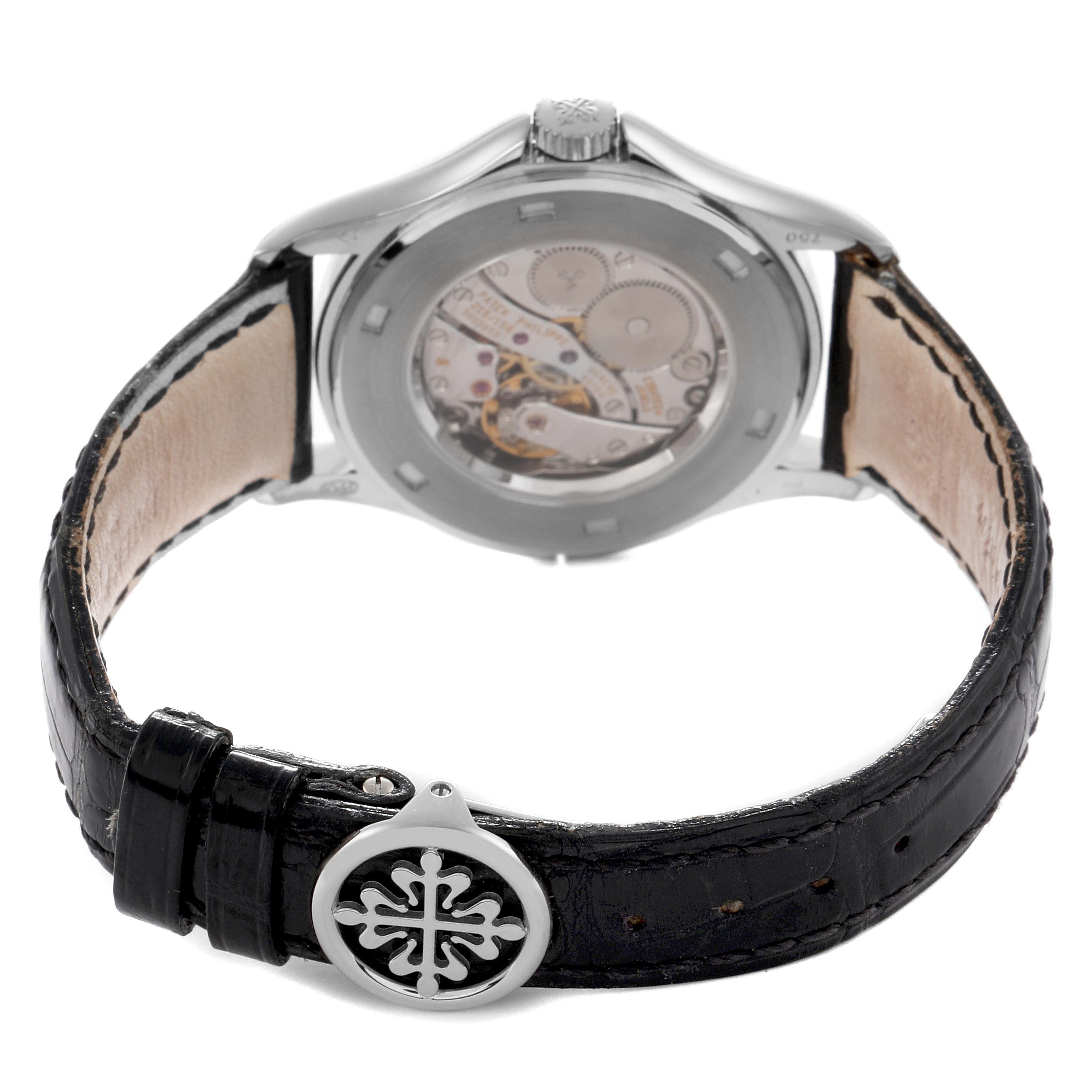 The image shows the back view of a Patek Philippe Calatrava 5134G Men
s White Gold White Dial 5134G Men
s White Gold White Dial watch, highlighting its open case back and leather strap with a decorative buckle.