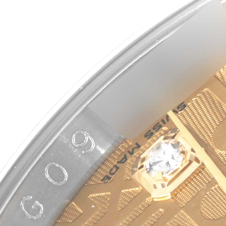 This close-up shows the engraved bezel and part of the diamond-set dial of a Rolex Datejust 116243 Men's Steel and Gold (two tone) Champagne Dial 116243 Men's Steel and Gold (two tone) Champagne Dial watch.