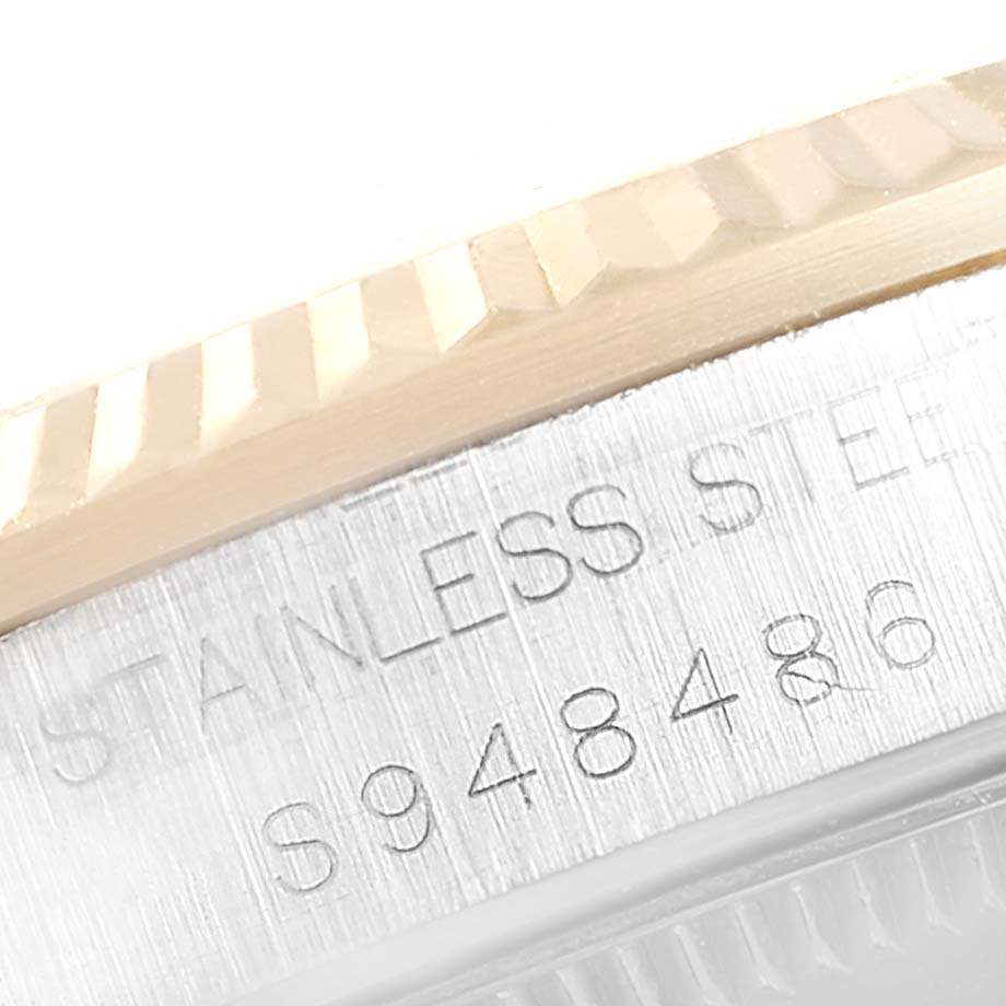 The image shows a close-up of the fluted bezel and engraved serial number of a Mid-Size Rolex watch.