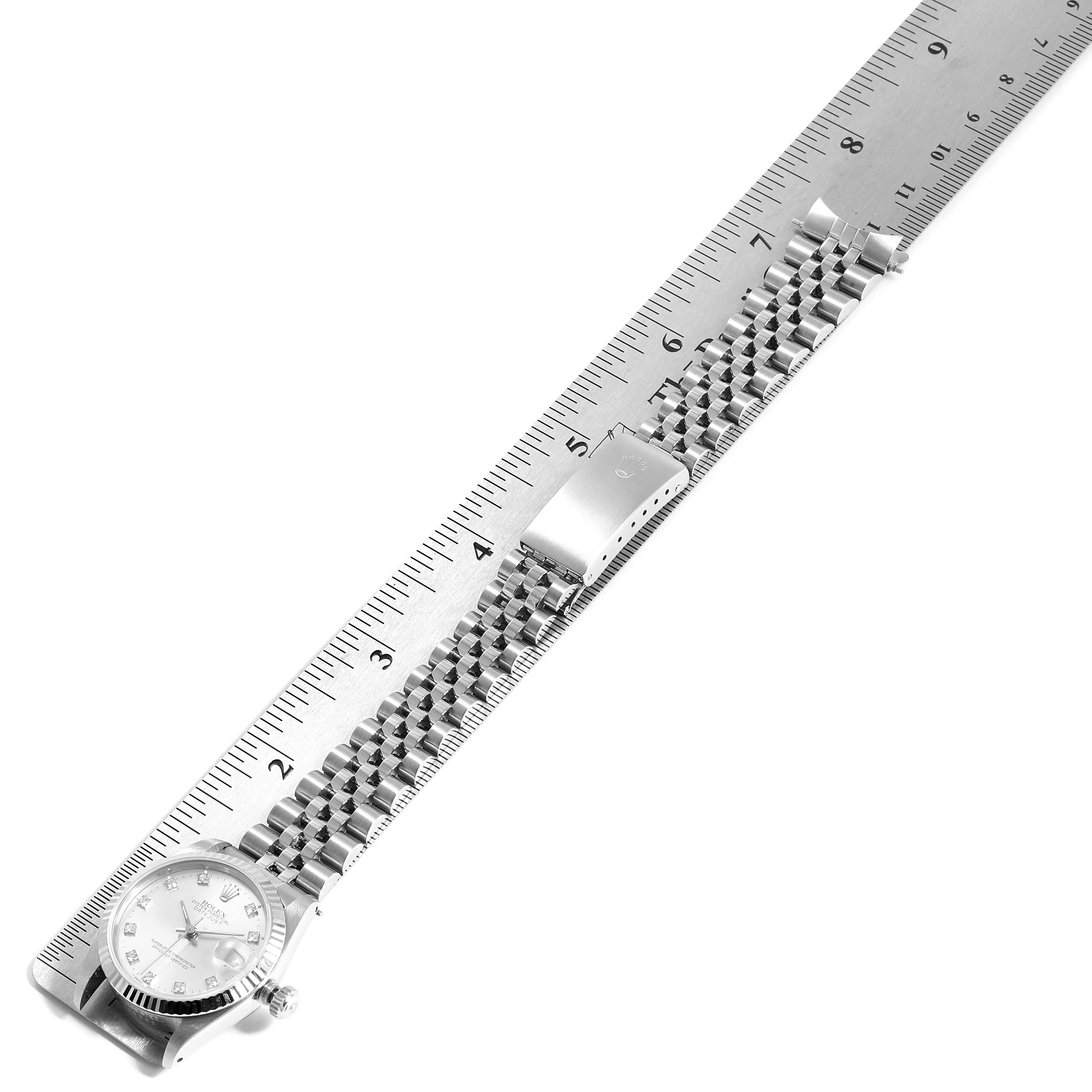 The image shows a Rolex Mid-Size 68274 Women
s Stainless Steel Silver Dial 68274 Women
s Stainless Steel Silver Dial model watch laid flat against a ruler, highlighting the band and clasp.