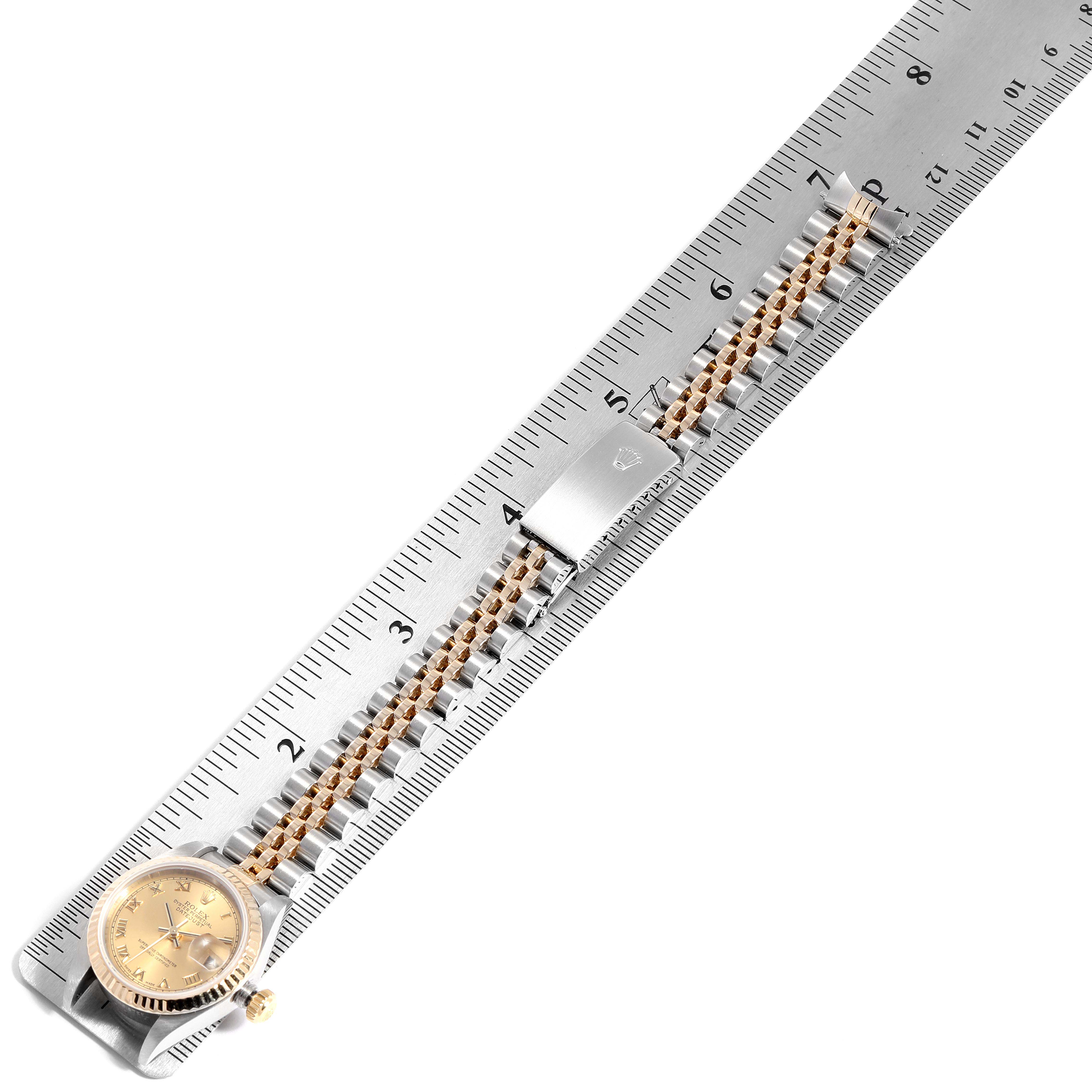 The image shows a Rolex Datejust 79173 Women
s Steel and Gold (two tone) Champagne Dial 79173 Women
s Steel and Gold (two tone) Champagne Dial watch laid flat, with a focus on its band and clasp, alongside a ruler for measurement.