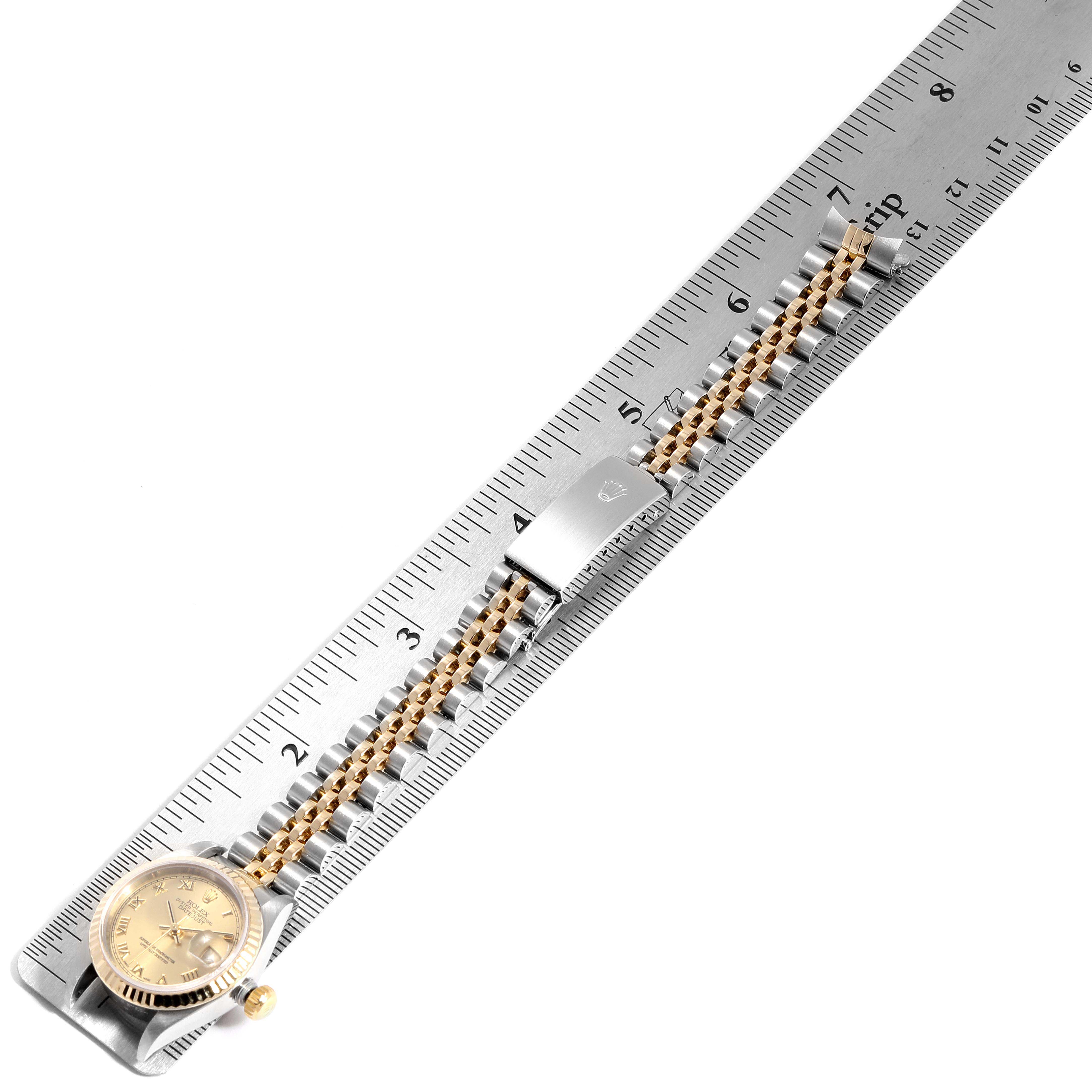 The image shows a Rolex Datejust 79173 Women
s Steel and Gold (two tone) Champagne Dial 79173 Women
s Steel and Gold (two tone) Champagne Dial watch laid flat on a ruler, displaying its face and entire bracelet.