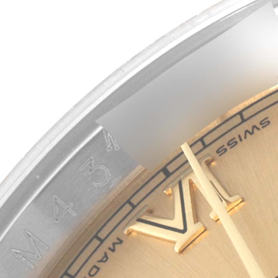 This close-up image of a Rolex Datejust 116233 Men's Steel and Gold (two tone) Champagne Dial 116233 Men's Steel and Gold (two tone) Champagne Dial watch features the edge of the dial, including the Roman numeral VI, and part of the bezel.