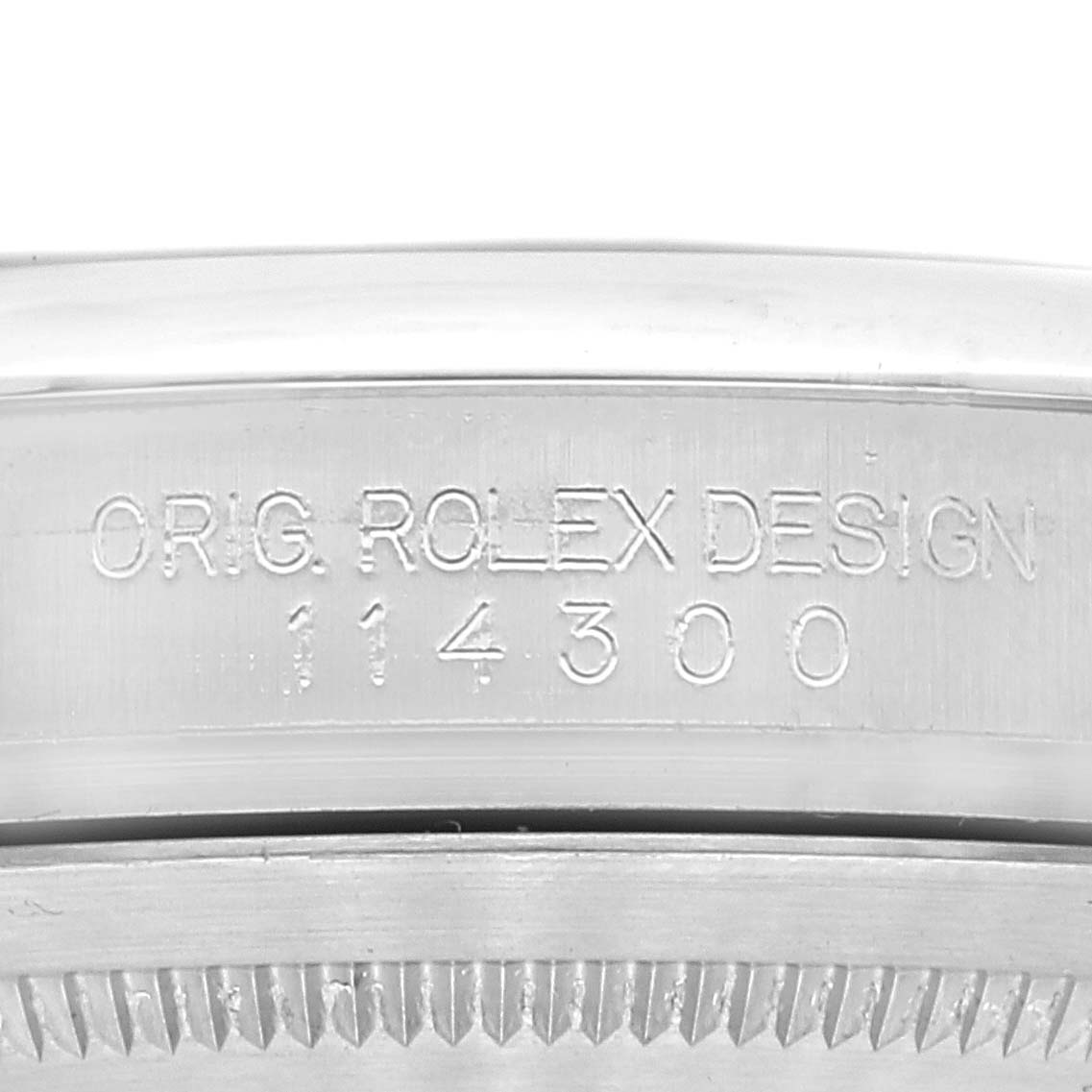 The image shows a close-up of the side of a Rolex Oyster Perpetual 114300 Men's Stainless Steel Blue Dial 114300 Men's Stainless Steel Blue Dial watch casing, displaying the model number 114300 and "ORIG. ROLEX DESIGN".