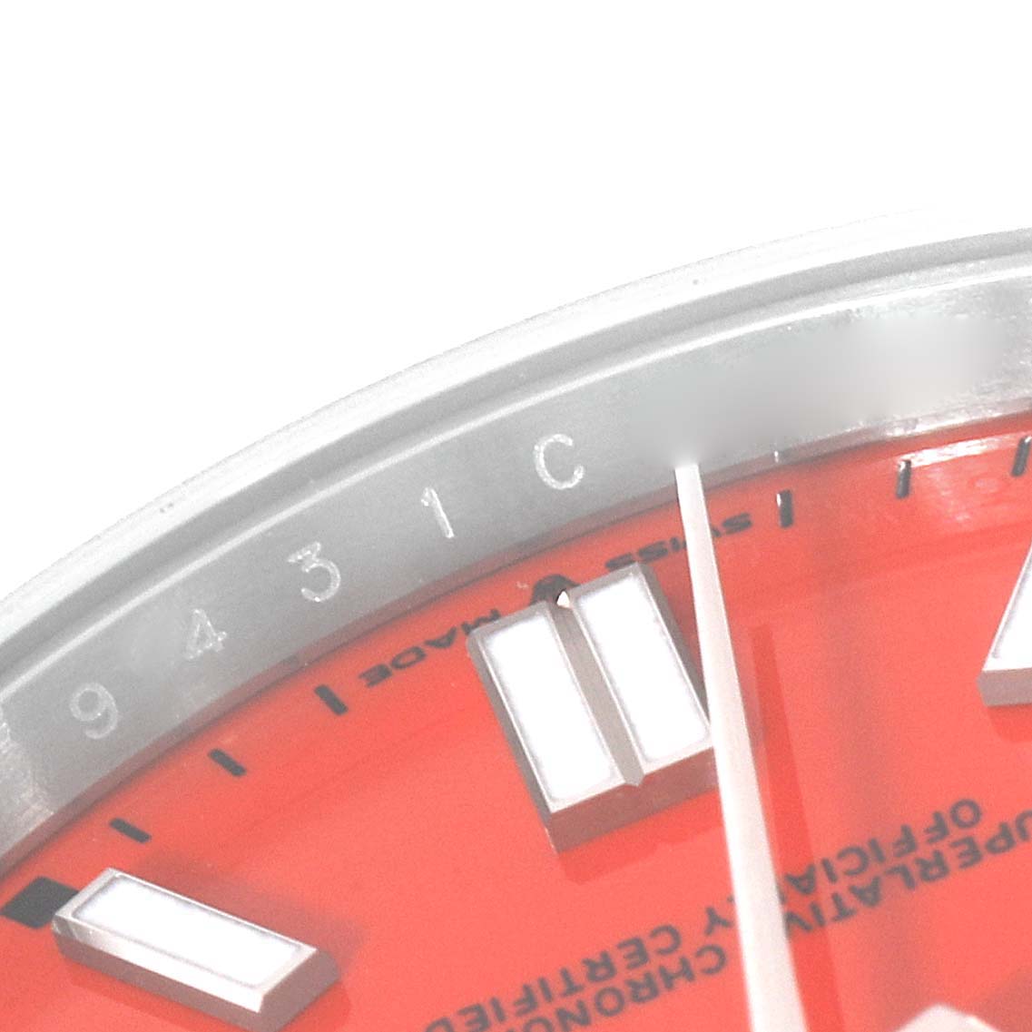 The image shows a close-up of the dial and bezel of a Rolex Oyster Perpetual 124300 Men
s Stainless Steel Red Dial 124300 Men
s Stainless Steel Red Dial watch, highlighting the hour markers and part of the bezel inscriptions.