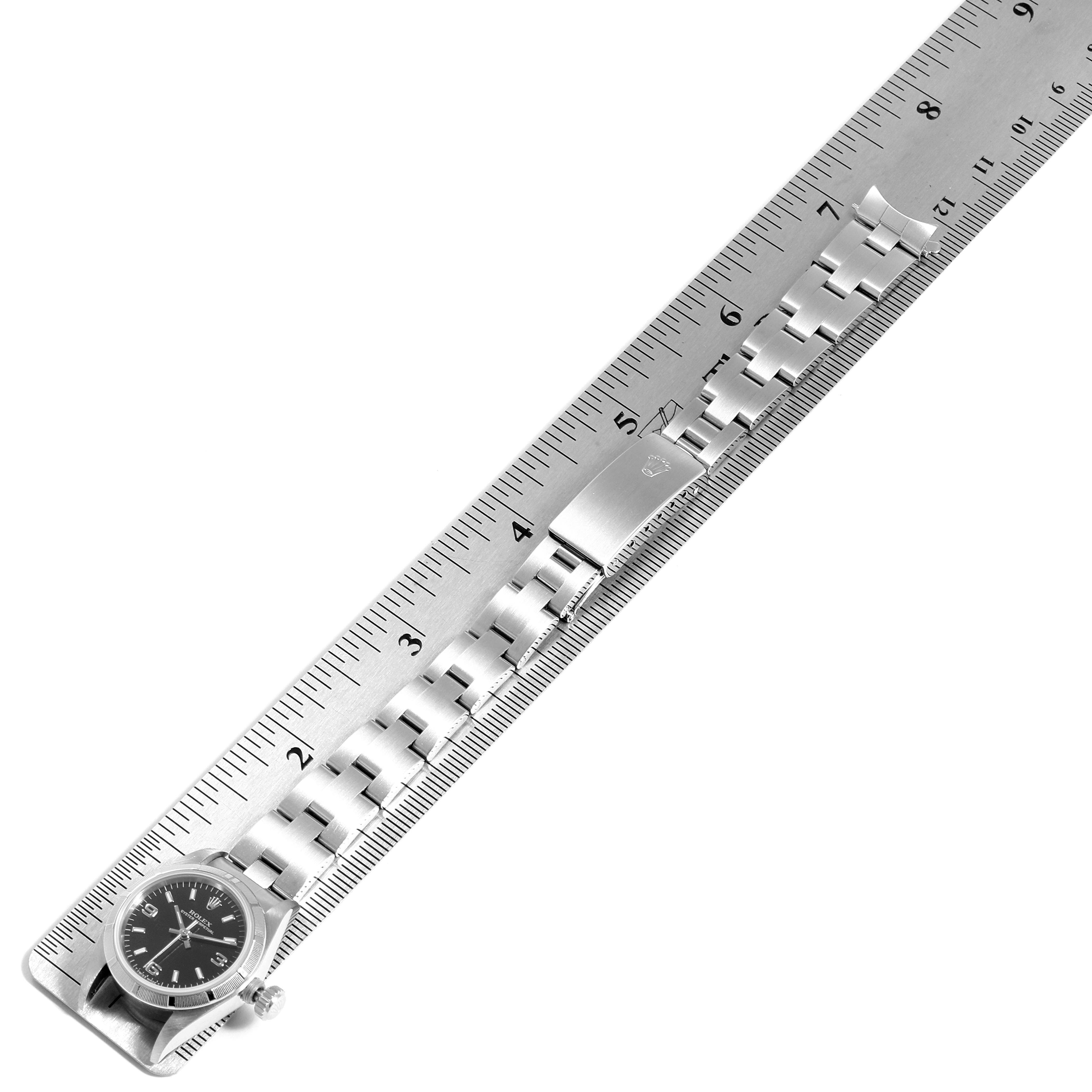 The Rolex Oyster Perpetual 67230 Women
s Stainless Steel Black Dial 67230 Women
s Stainless Steel Black Dial watch is shown from the top perspective with its band measured against a ruler.