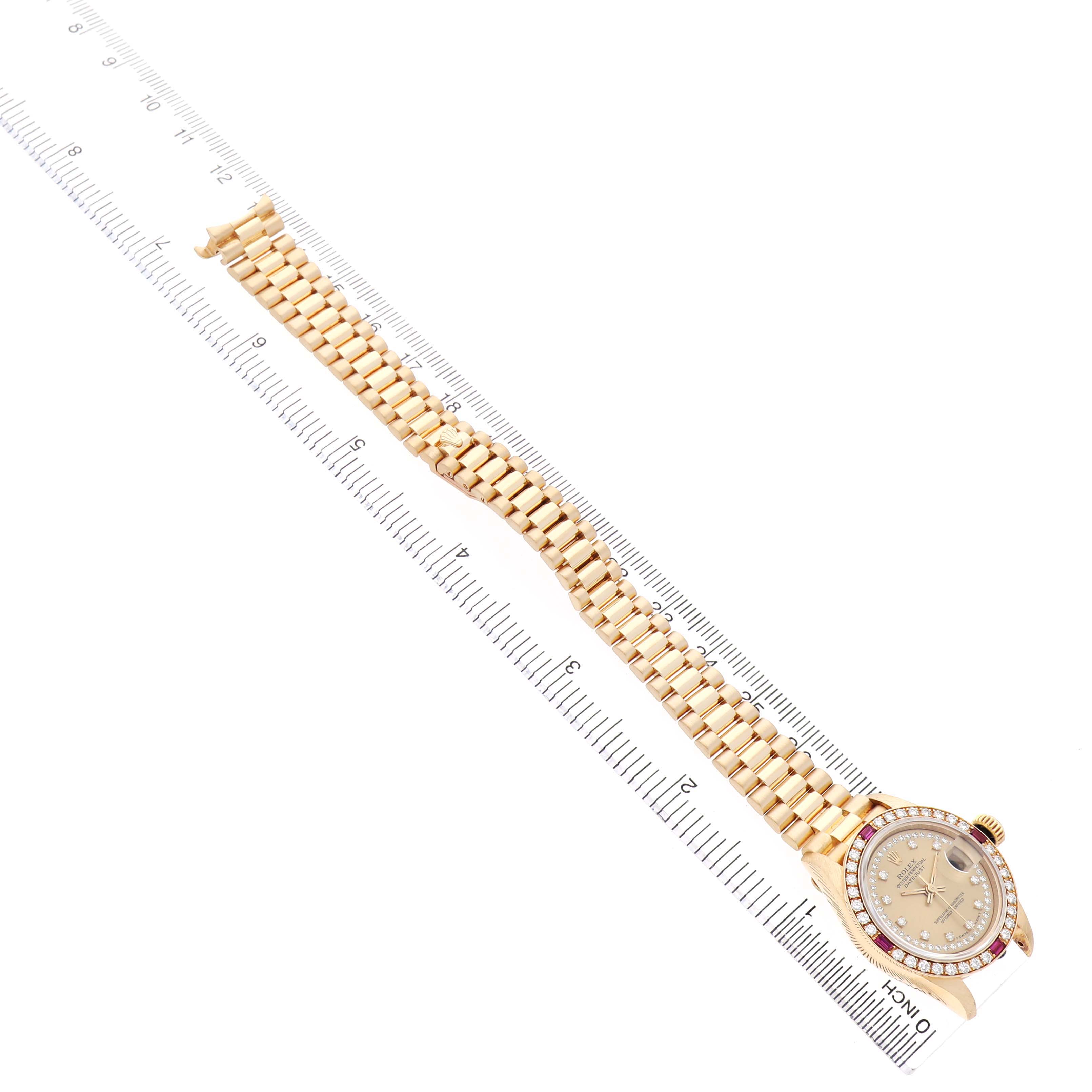 The Rolex President 69068 Women's Yellow Gold Champagne Dial model watch is shown angled, displaying its face, bezel, and full bracelet alongside a ruler for scale.