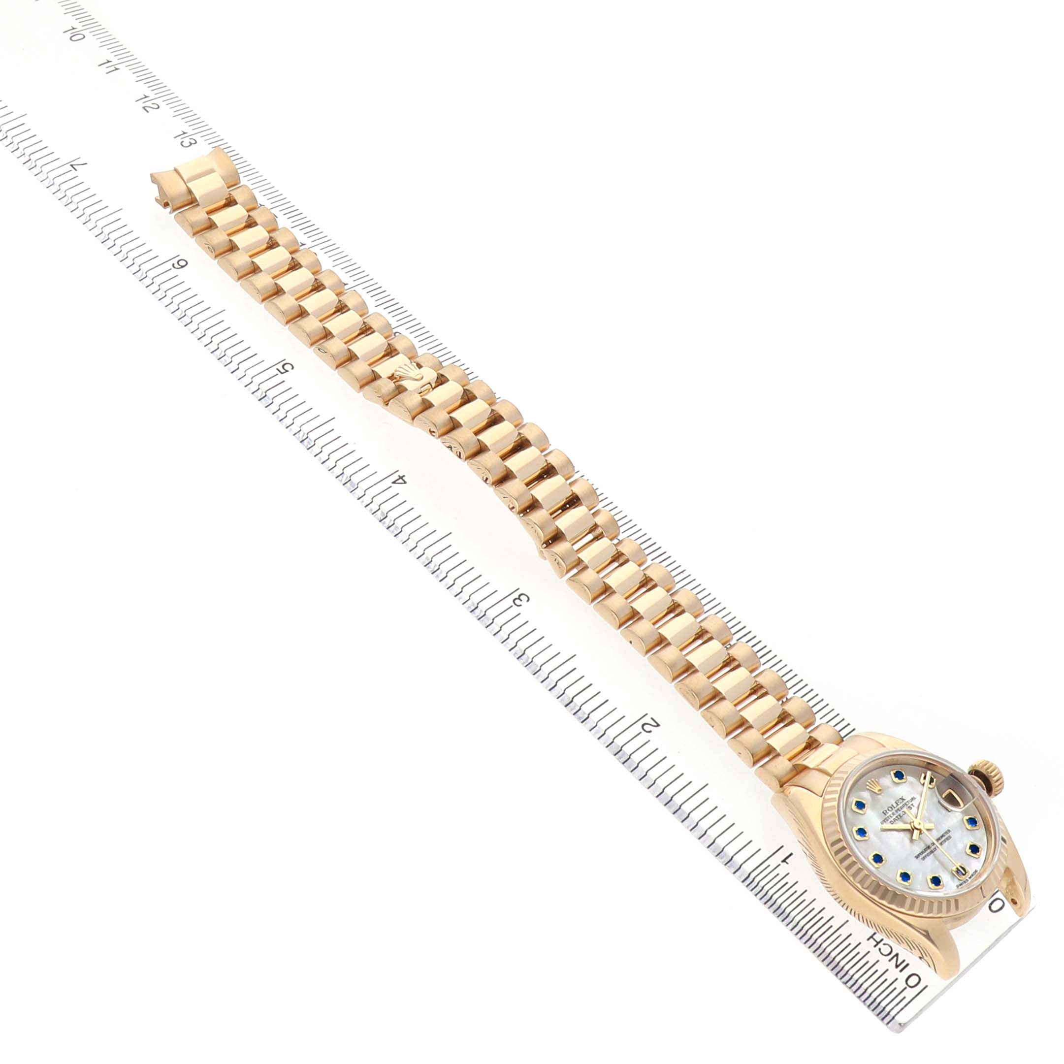 The Rolex President 179178 Men's Yellow Gold Mother of Pearl Dial model watch is shown at a diagonal angle, displaying the face, bezel, and full bracelet alongside a ruler.