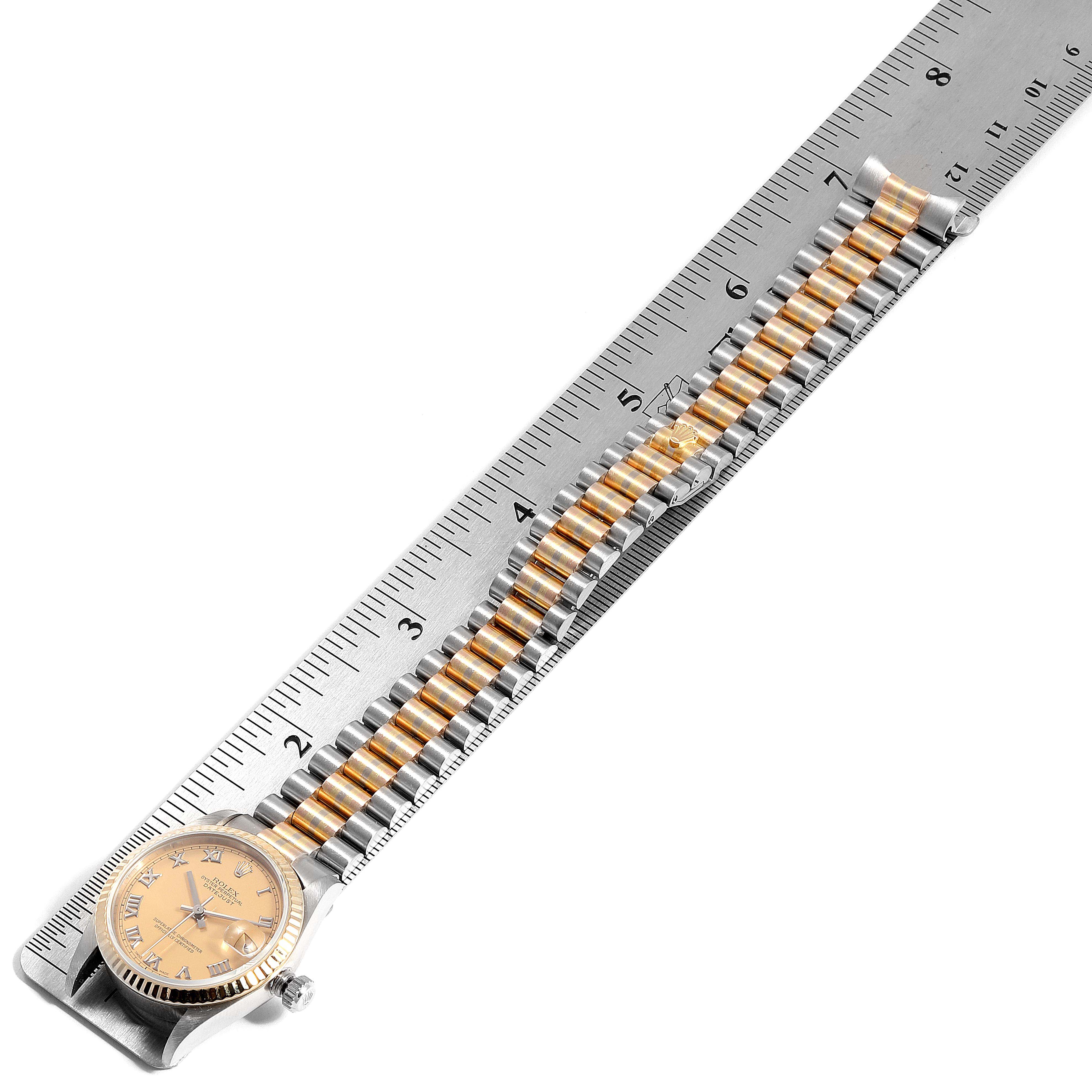 The image shows a Rolex President 78279 Women
s White Gold Brown Dial 78279 Women
s White Gold Brown Dial watch with a gold dial and a two-tone band, measured against a ruler.