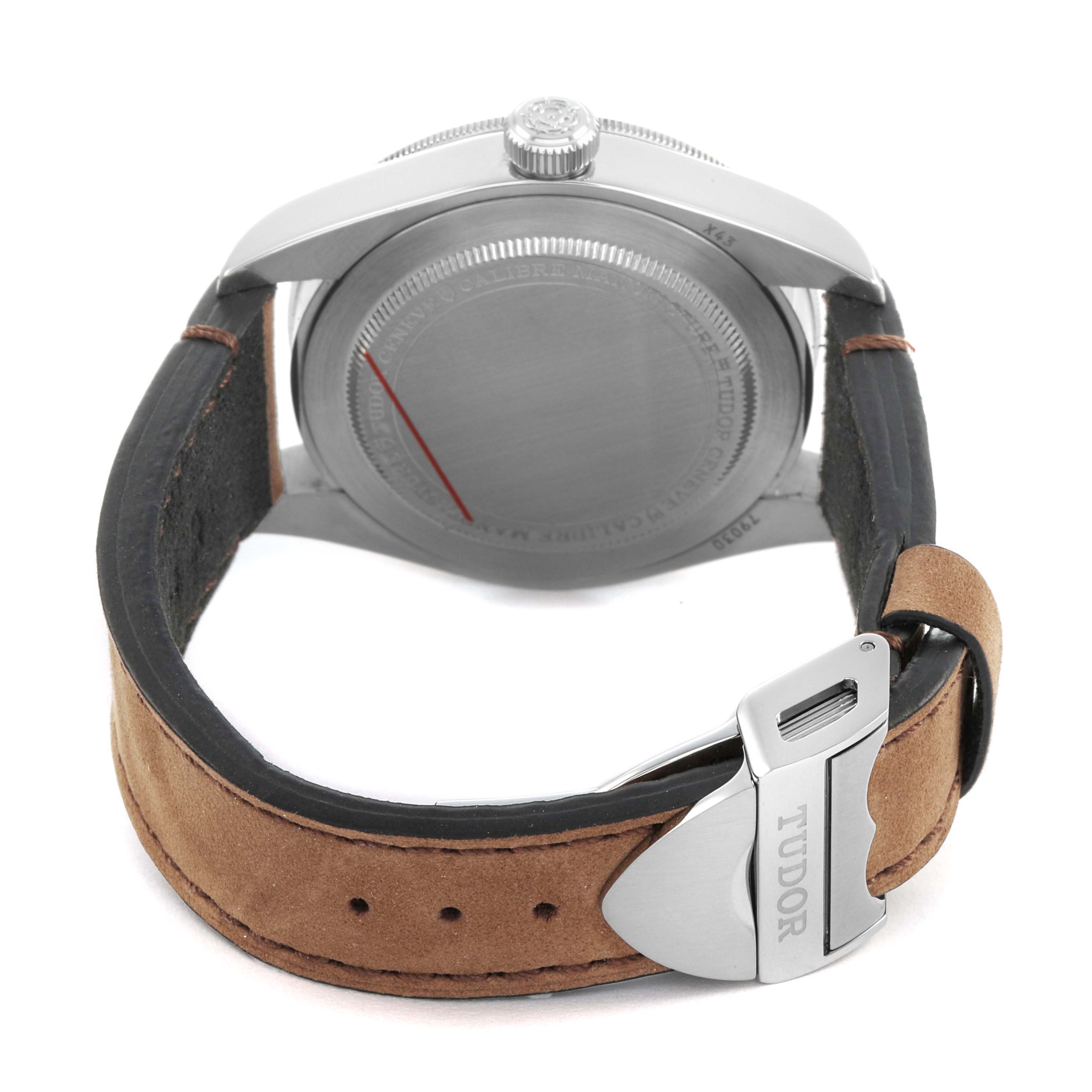 The Tudor Heritage Black Bay 79030 Men's Stainless Steel Black Dial watch is shown from the back, highlighting the case back, crown, and leather strap with Tudor clasp.