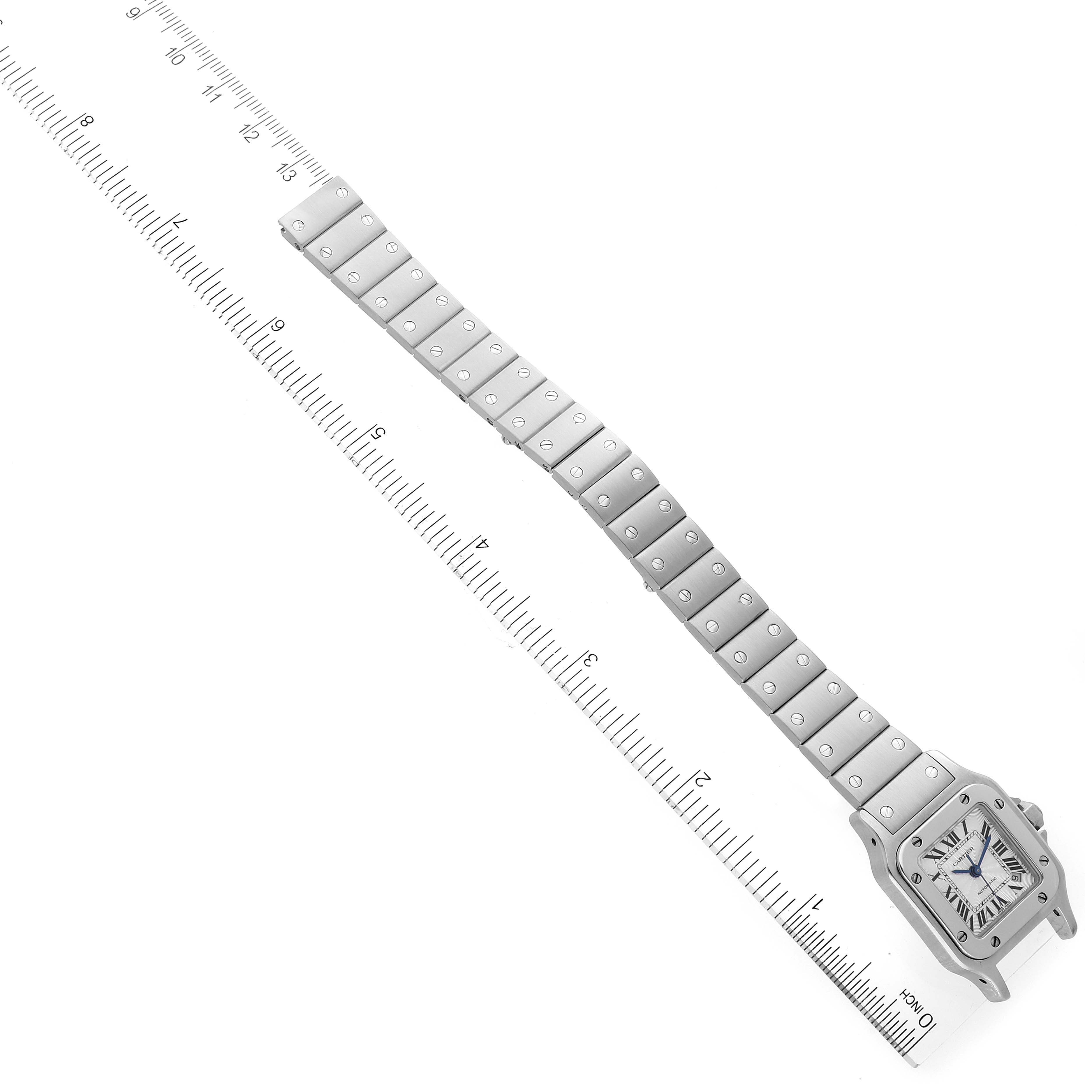 The image shows a top-down view of a Cartier Santos W20044D6 Women's Stainless Steel Silver Dial W20044D6 Women's Stainless Steel Silver Dial watch with a full metal bracelet and rulers on each side.