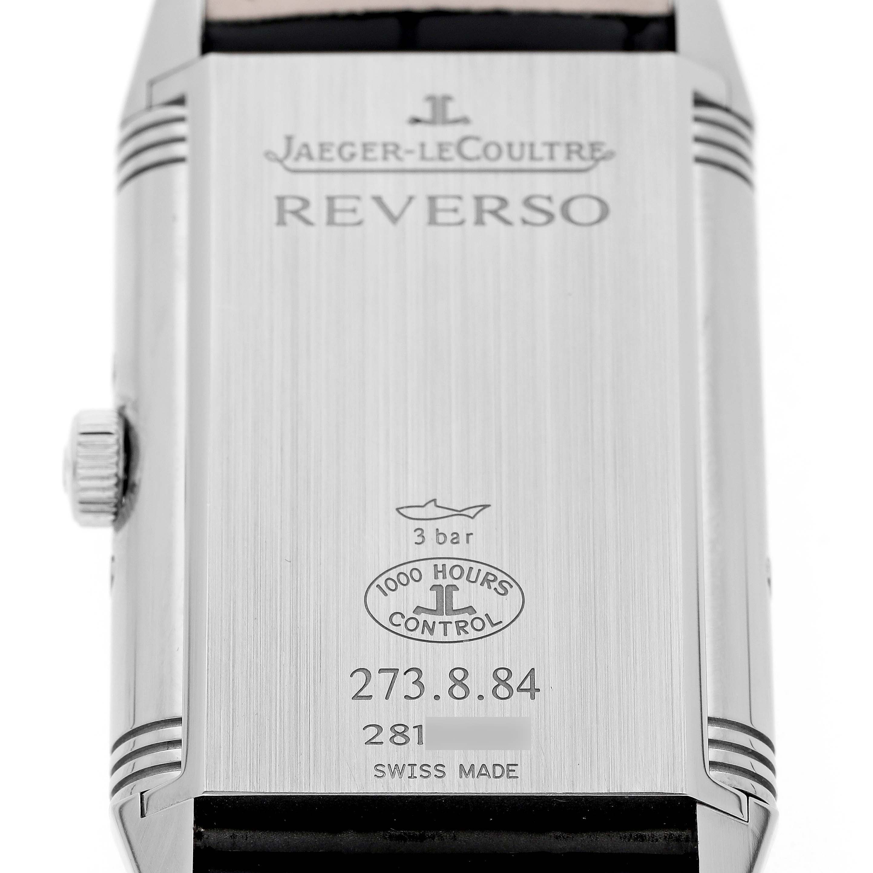 The image shows the back of the Jaeger-LeCoultre Reverso watch, including its crown and engraved details.