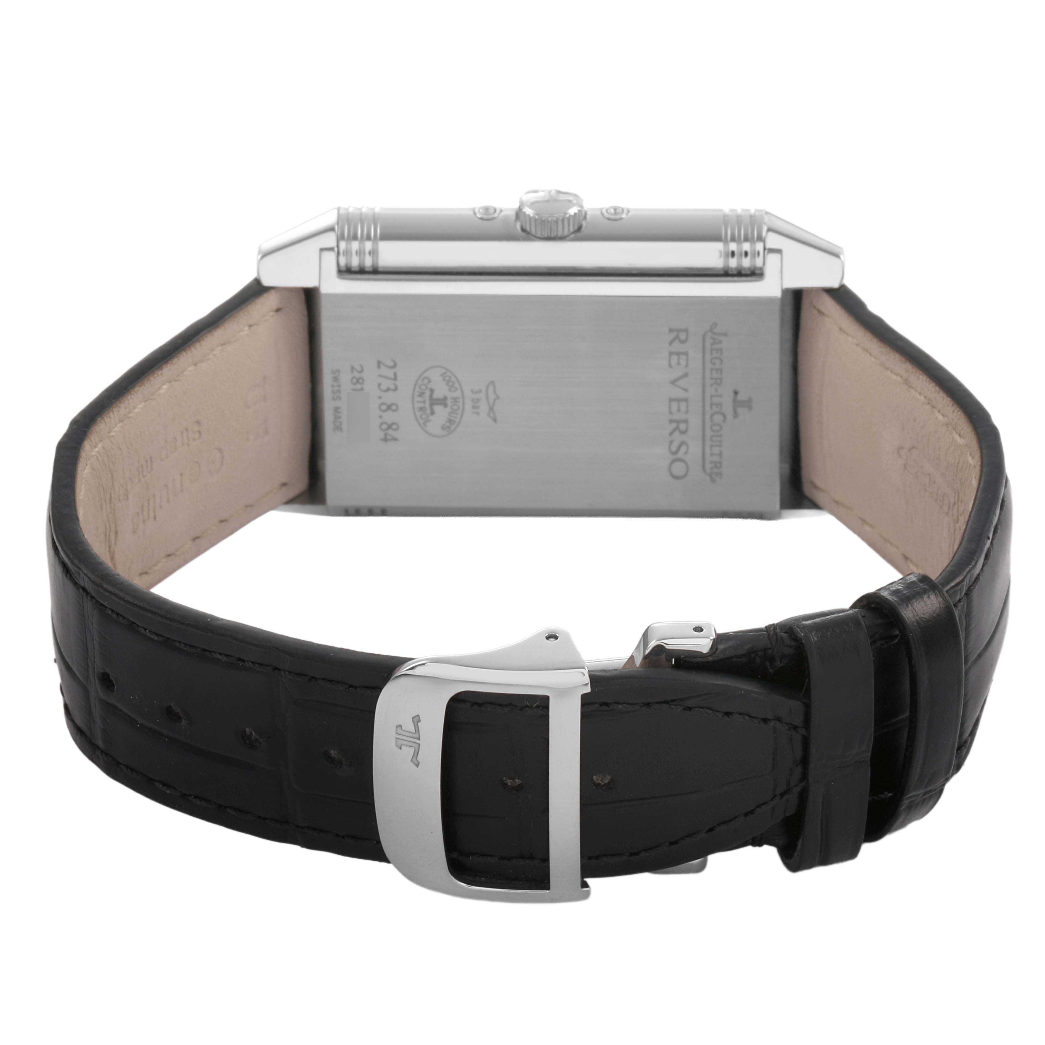 The Jaeger-LeCoultre Reverso watch is shown from the back, highlighting the strap, buckle, and case back detailing.