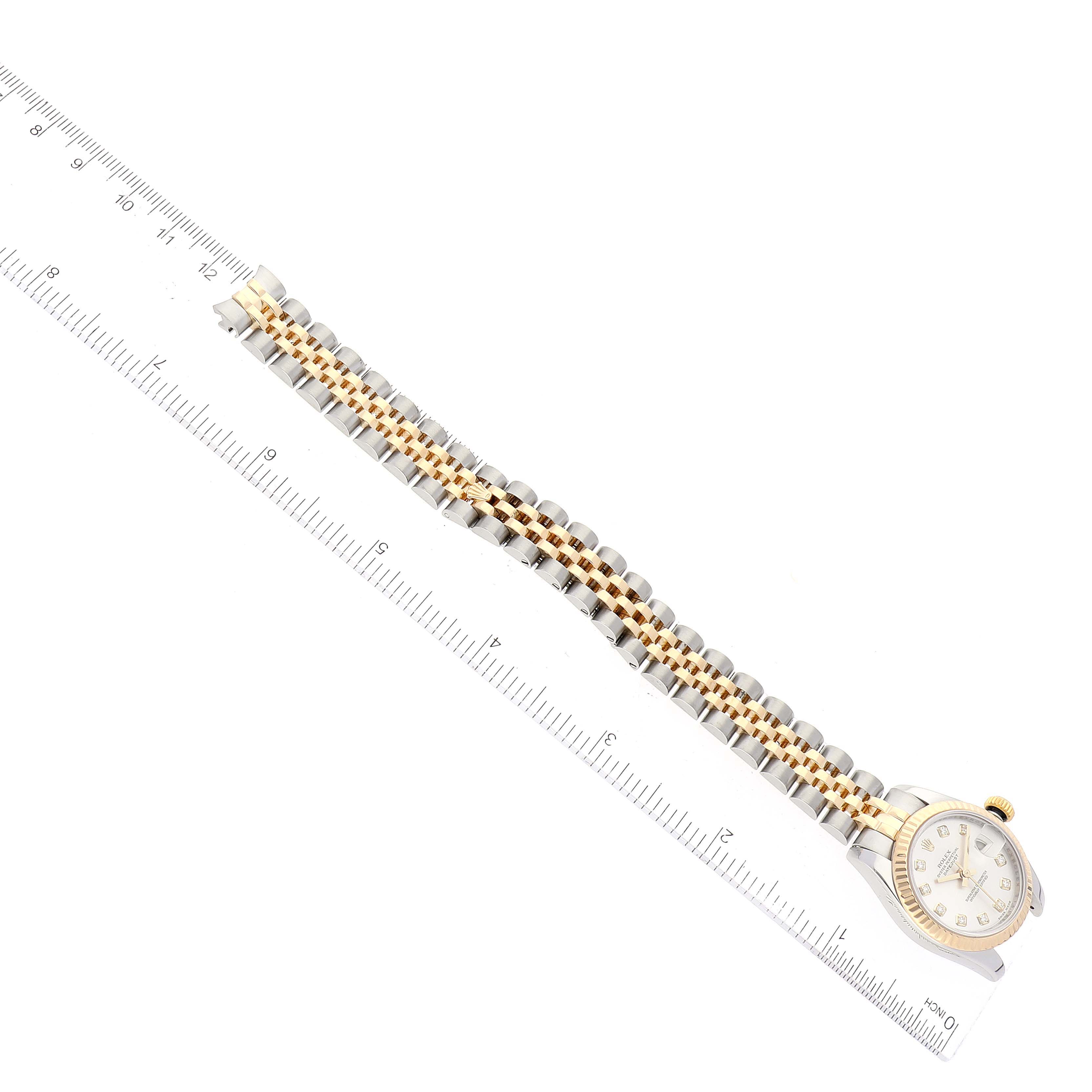 The image shows a top view of a Rolex Datejust 179173 Women's Steel and Gold (two tone) Silver Dial 179173 Women's Steel and Gold (two tone) Silver Dial watch, highlighting its face, crown, and two-tone bracelet alongside a ruler for scale.