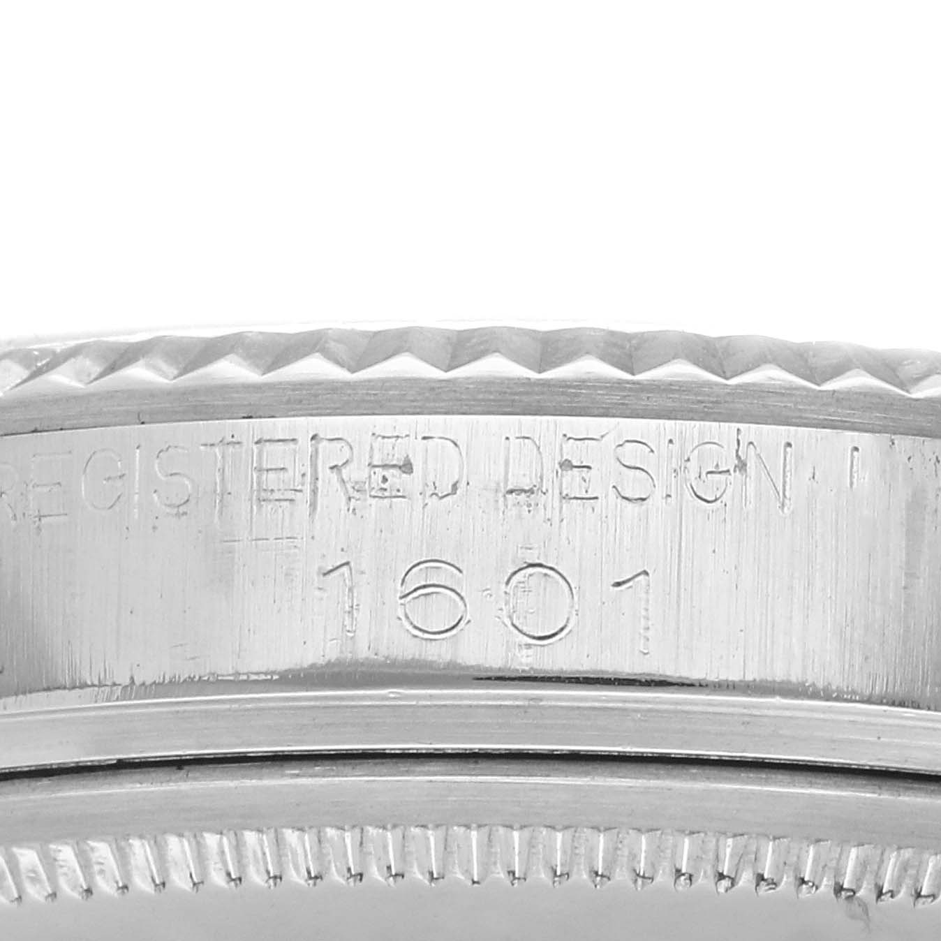 The image shows a close-up of the case edge of a Rolex Datejust 1601 Men
s Stainless Steel Silver Dial 1601 Men
s Stainless Steel Silver Dial watch, highlighting its fluted bezel and engraving.