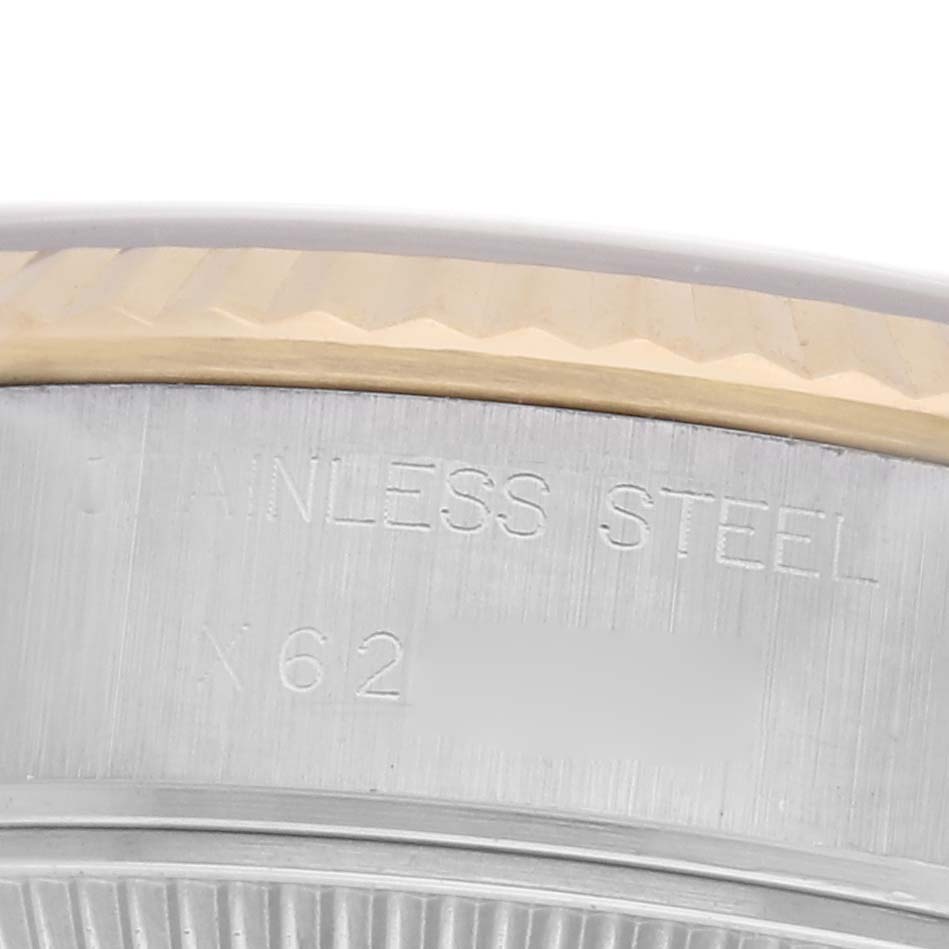The image shows a close-up of the side of a Rolex Datejust 69173 Women
s Steel and Gold (two tone) Red Dial 69173 Women
s Steel and Gold (two tone) Red Dial watch, focusing on the bezel and "Stainless Steel" engraving.