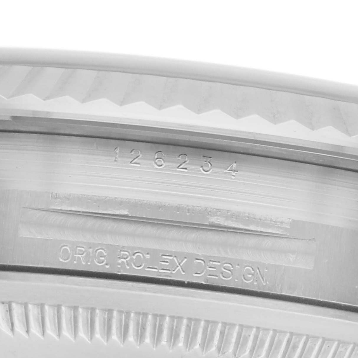The image shows a close-up of a Rolex Datejust 126234 Men's Stainless Steel White Dial 126234 Men's Stainless Steel White Dial watch’s case edge with engravings, including the model number.