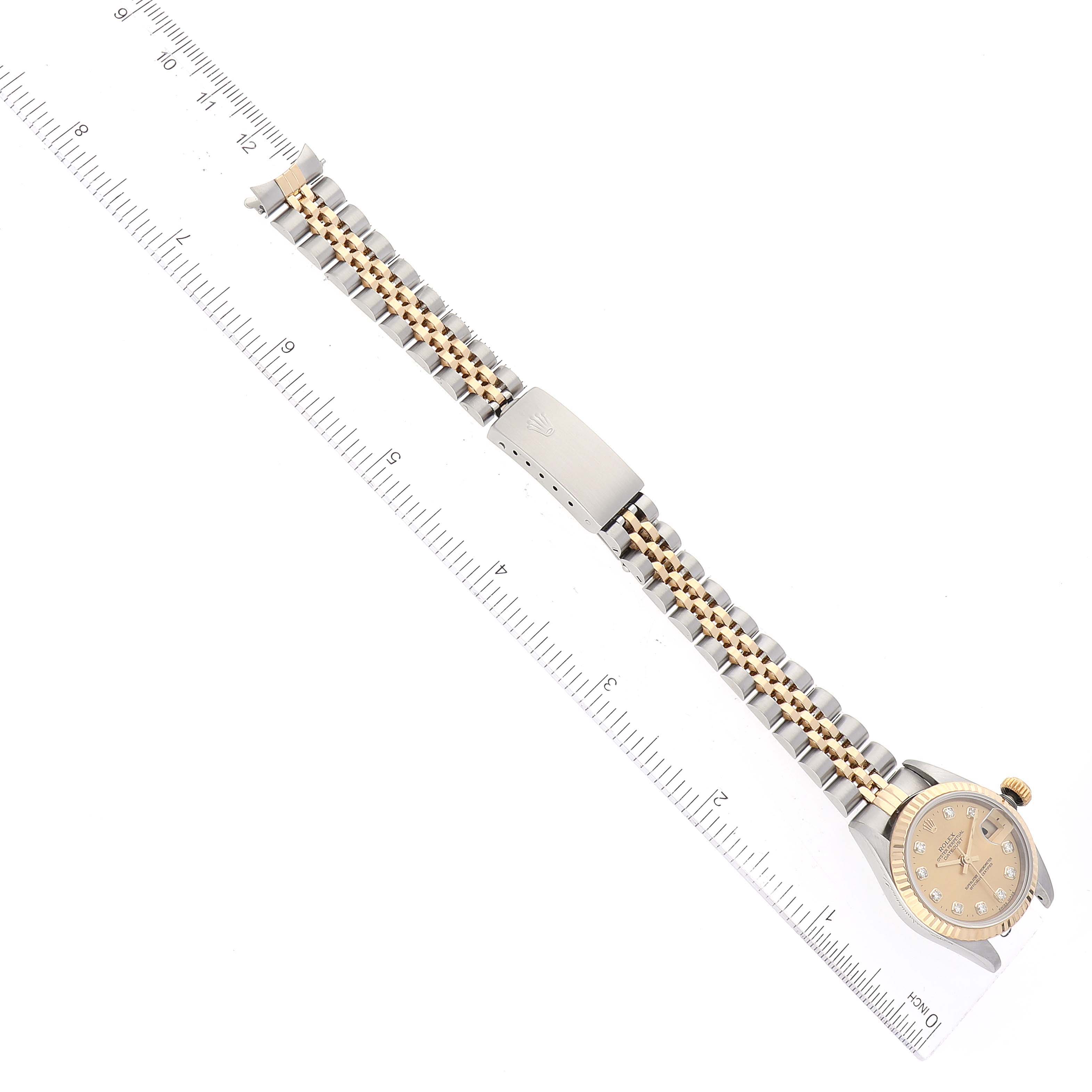 This image shows a Rolex Datejust 69173 Women's Steel and Gold (two tone) Champagne Dial 69173 Women's Steel and Gold (two tone) Champagne Dial watch laid flat with a ruler for scale, displaying the face, bezel, and Jubilee bracelet with clasp.