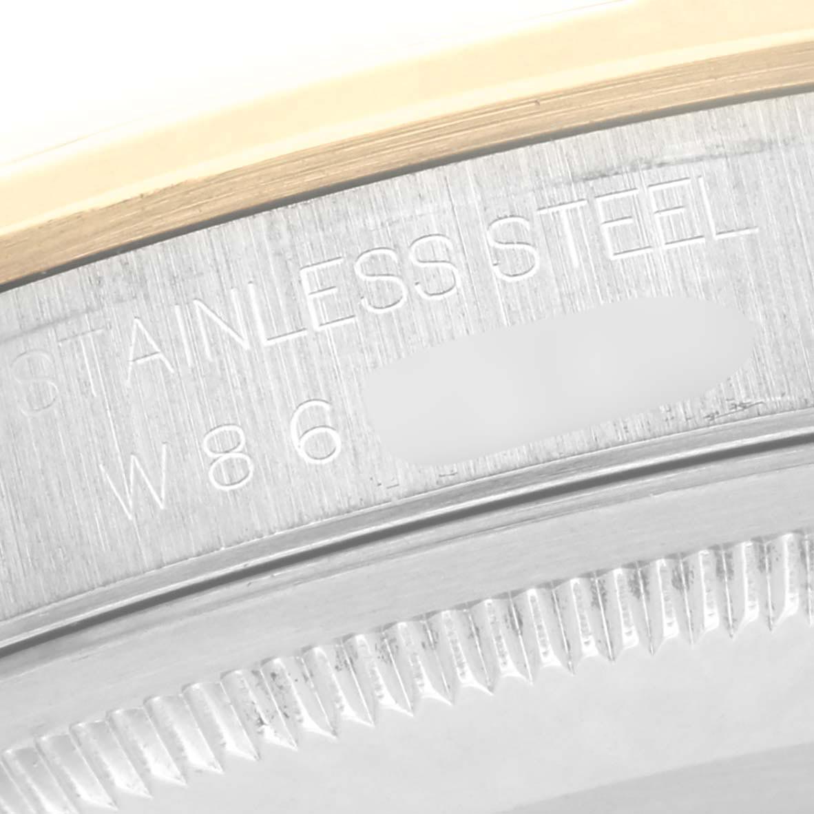 The image shows a close-up of the Rolex Datejust 16203 Men
s Steel and Gold (two tone) Grey Dial 16203 Men
s Steel and Gold (two tone) Grey Dial
s stainless steel back with engravings and part of the fluted bezel.