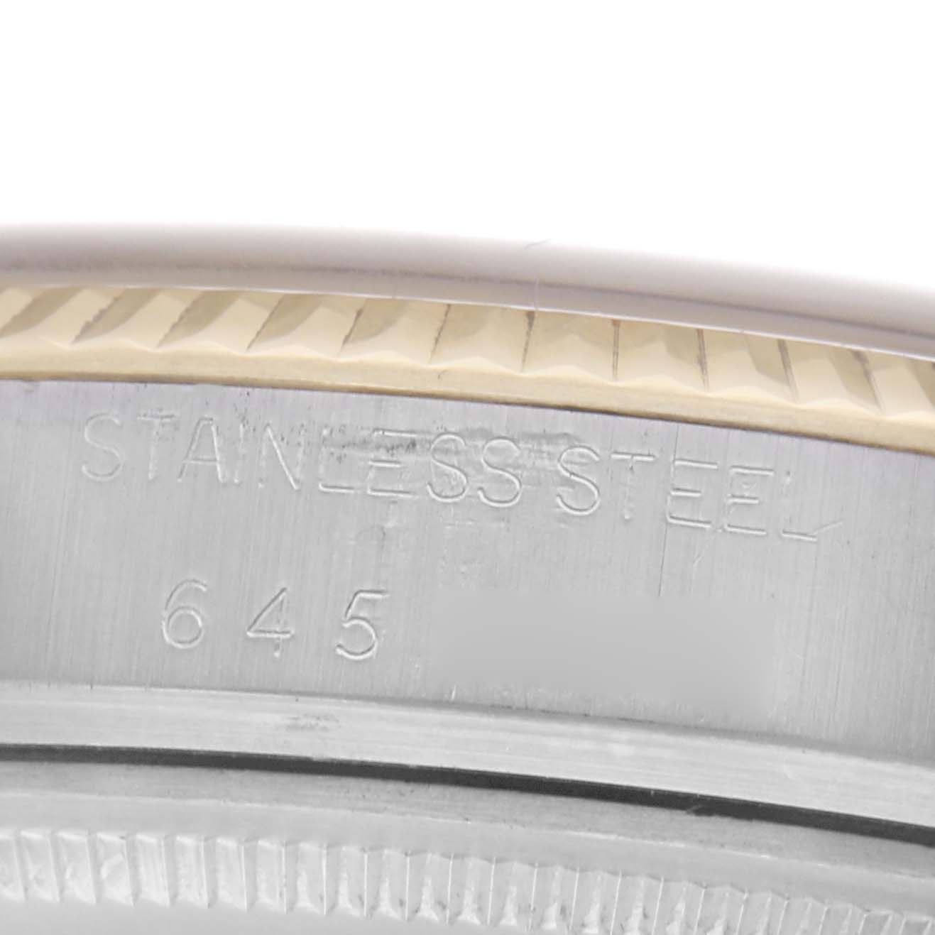 The image shows a close-up of the side of a Rolex Datejust 16013 Men
s Steel and Gold (two tone) Champagne Dial 16013 Men
s Steel and Gold (two tone) Champagne Dial watch case, highlighting the "STAINLESS STEEL" engraving.