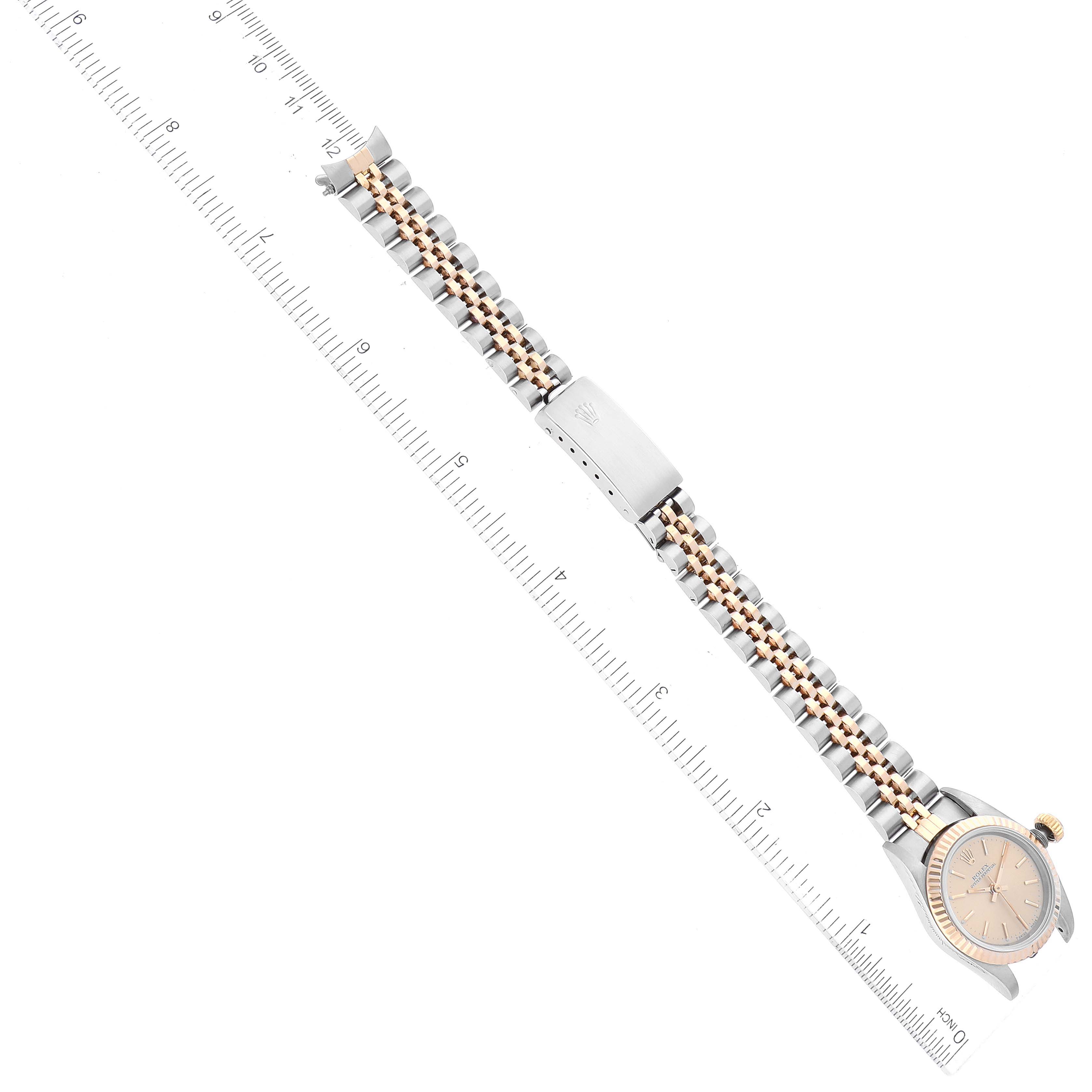 The image shows a Rolex Oyster Perpetual 67193 Women's Steel and Gold (two tone) Champagne Dial 67193 Women's Steel and Gold (two tone) Champagne Dial watch laid flat, with its dial, crown, and bracelet visible alongside a ruler for scale.