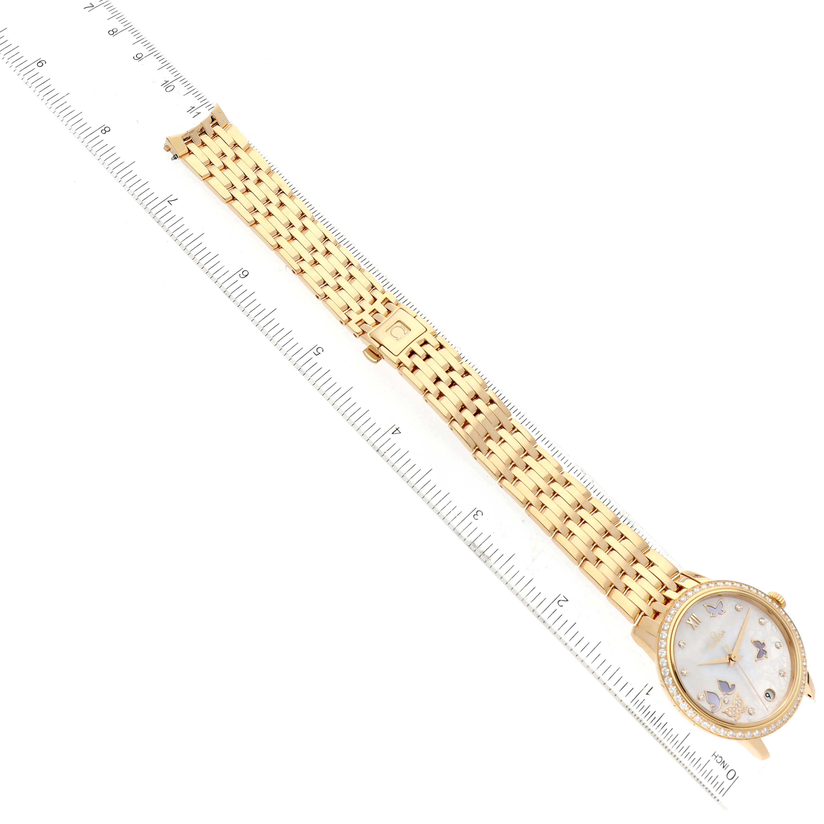 The image shows an Omega 424.55.33.20.55.005 Women's Yellow Gold Mother of Pearl Dial 424.55.33.20.55.005 Women's Yellow Gold Mother of Pearl Dial DeVille Prestige Yellow Gold Mother of Pearl Diamond Watch 424.55.33.20.55.005 laid flat with a ruler beside it.