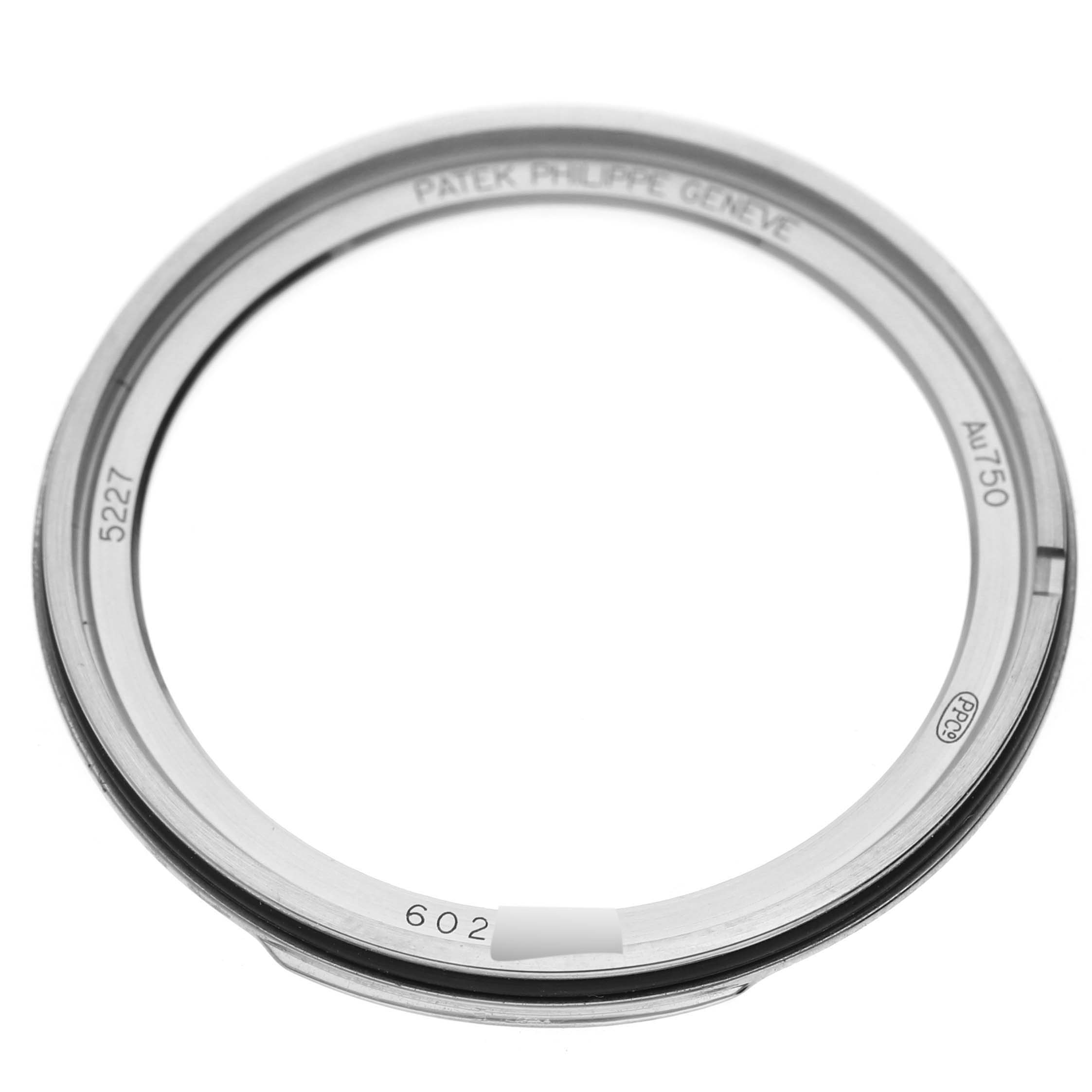 The image shows a close-up of a Patek Philippe Calatrava 5227G-001 Men's White Gold Beige Dial 5227G-001 Men's White Gold Beige Dial model watch bezel, displaying reference numbers and brand inscriptions.