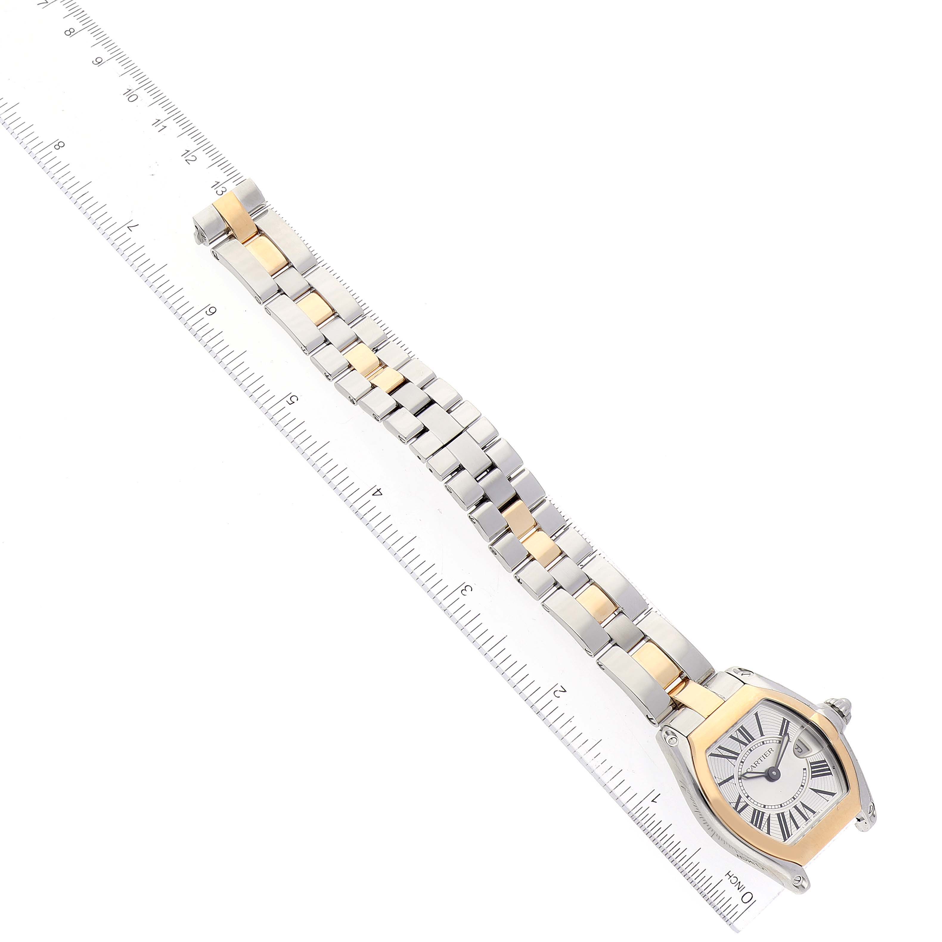 The Cartier Roadster W62026Y4 Women's Steel and Gold (two tone) Silver Dial W62026Y4 Women's Steel and Gold (two tone) Silver Dial watch is shown at a diagonal angle, featuring its face, bezel, and entire bracelet with a ruler for scale.