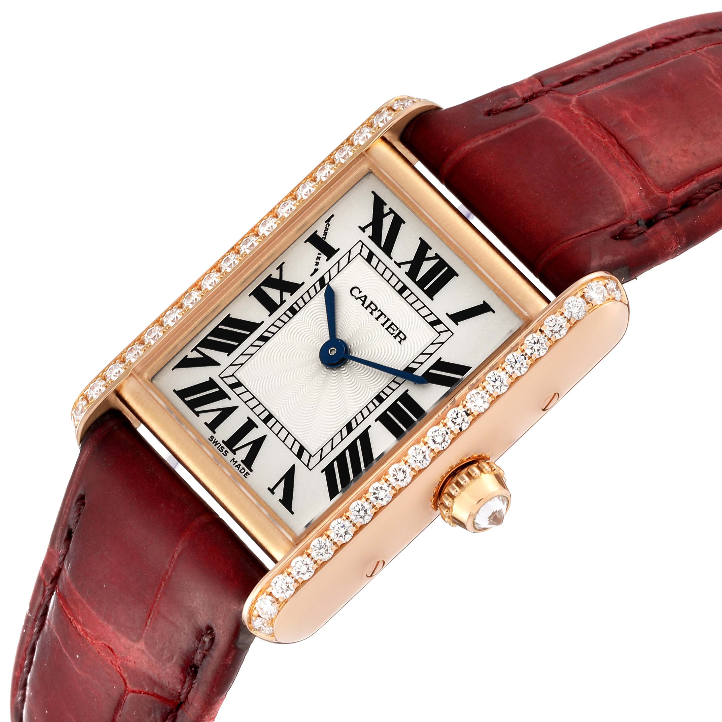The image shows a Cartier Tank Louis WJTA0010 Women
s Rose Gold Silver Dial WJTA0010 Women
s Rose Gold Silver Dial watch with a rectangular face, gold casing, diamond accents, and a red leather strap from an angled top view.