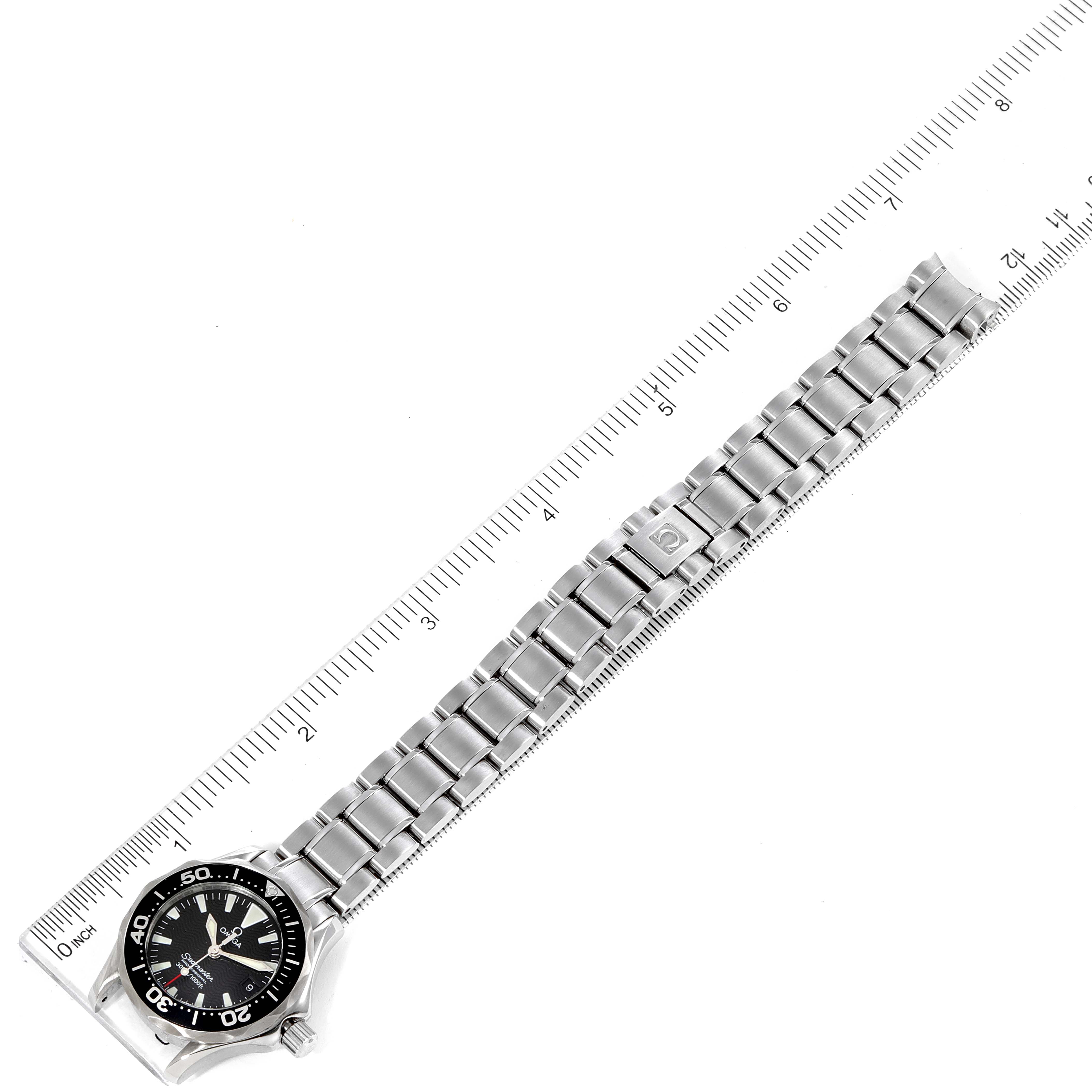 This image shows the Omega 2284.50.00 Women's Stainless Steel Black Dial 2284.50.00 Women's Stainless Steel Black Dial Seamaster Diver 300M 28mm Steel Ladies Watch 2284.50.00 laid flat next to a ruler.