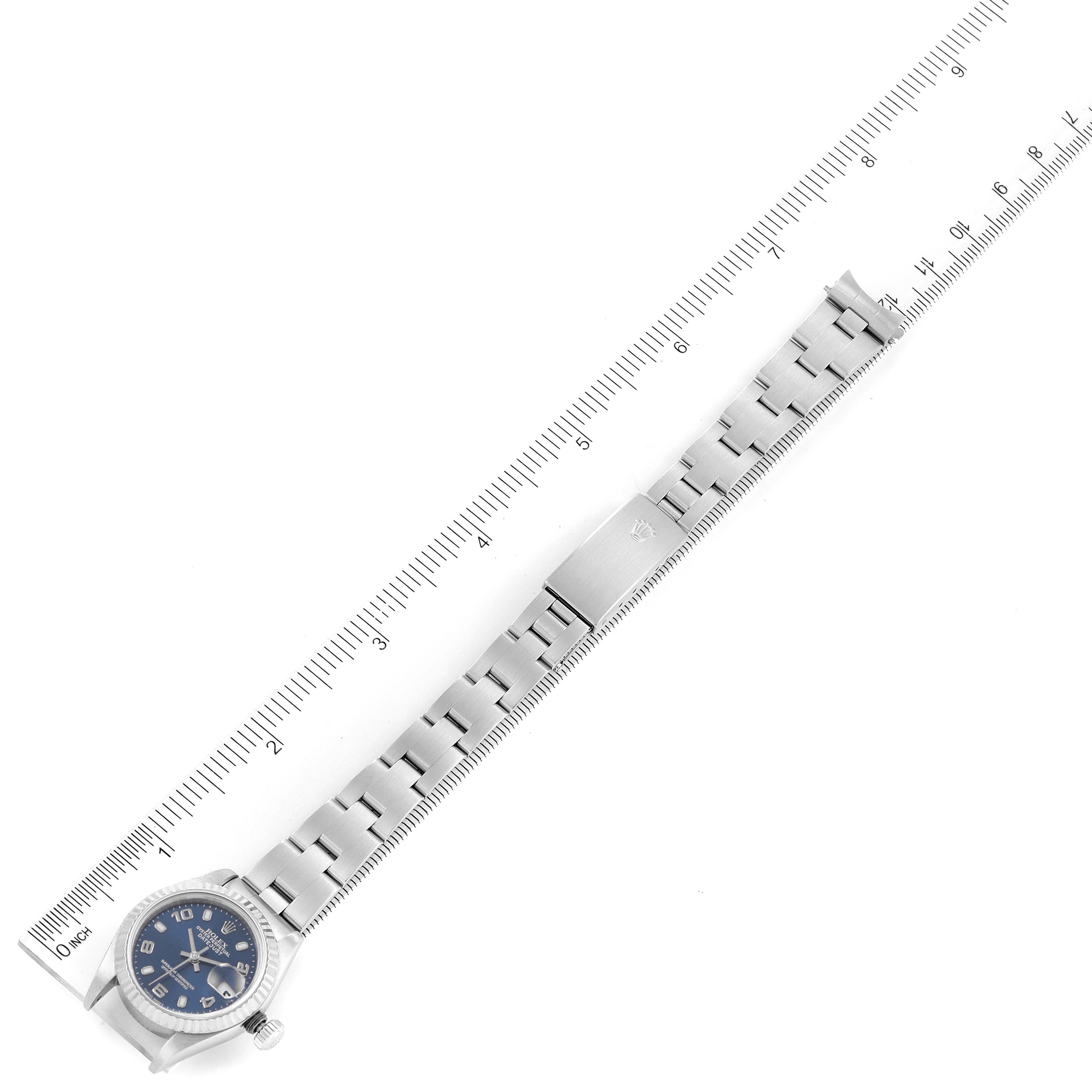 The image shows a Rolex Datejust 79174 Women's Stainless Steel Blue Dial 79174 Women's Stainless Steel Blue Dial watch laid flat with its bracelet extended alongside a ruler for measurement.