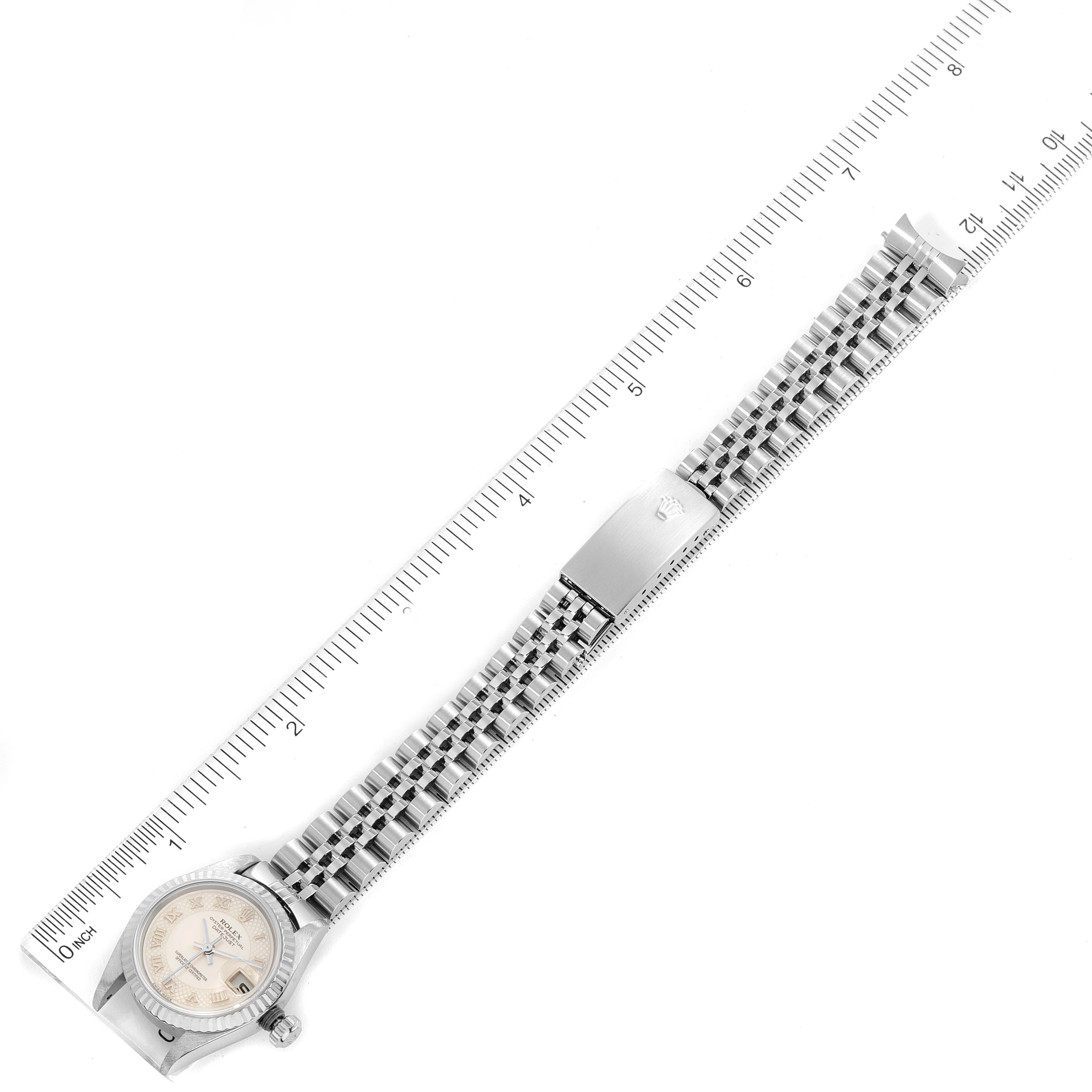 This Rolex Datejust 79174 Women
s Stainless Steel Mother of Pearl Dial 79174 Women
s Stainless Steel Mother of Pearl Dial watch is shown from a top-down angle, highlighting the face, bracelet, and clasp against a ruler for scale.