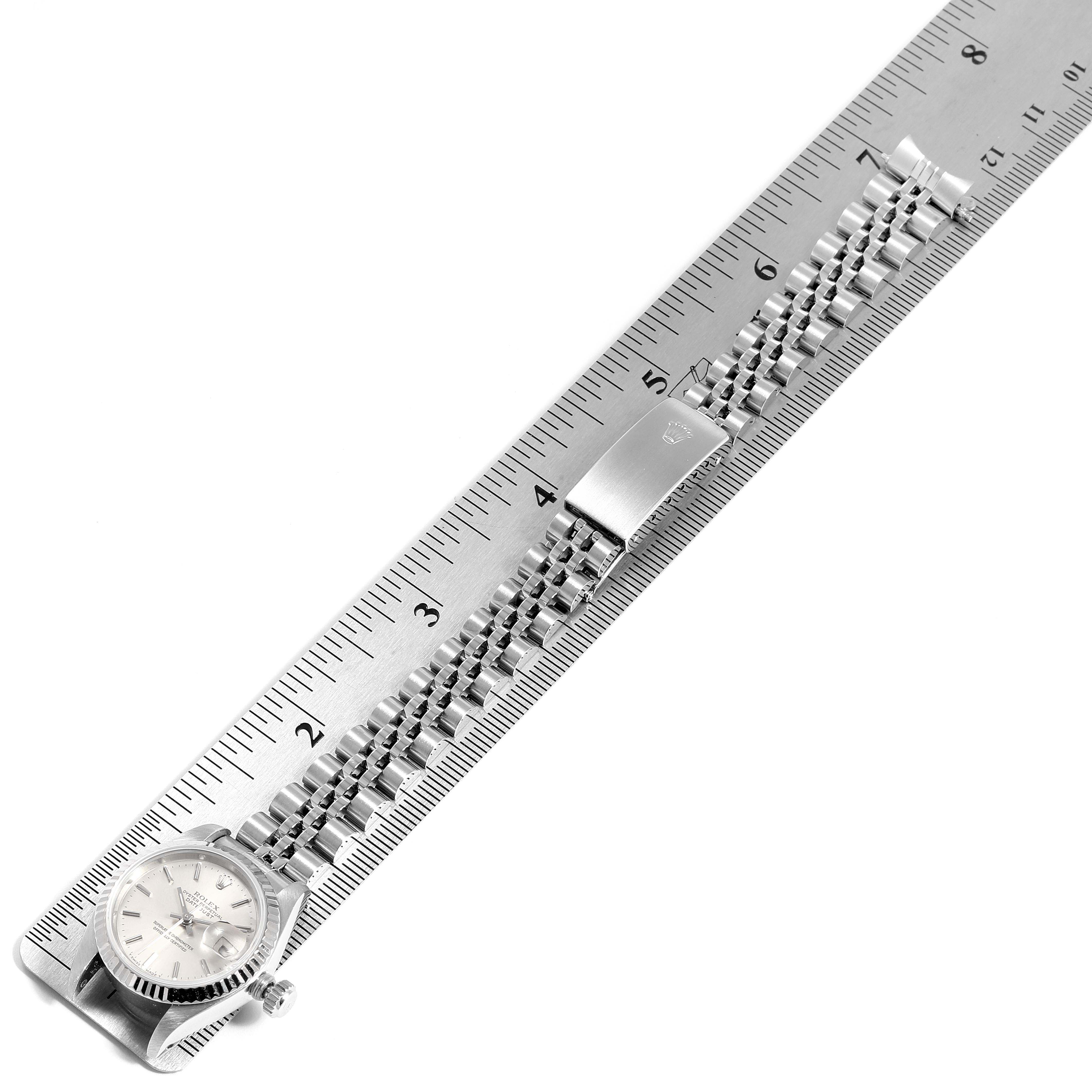 The image shows a top-down view of a Rolex Datejust 69174 Women
s Stainless Steel Silver Dial 69174 Women
s Stainless Steel Silver Dial watch, including the dial and the bracelet laid along a ruler.