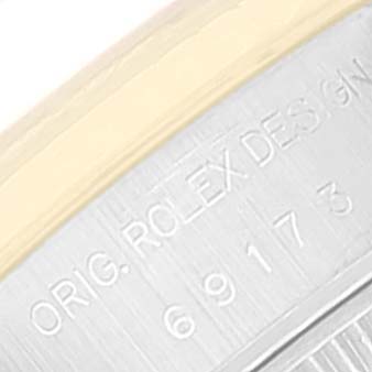 This close-up image of a Rolex Datejust 69173 Women's Steel and Gold (two tone) Black Dial 69173 Women's Steel and Gold (two tone) Black Dial shows the engraved text on its case, including "ORIG. ROLEX DESIGN" and a serial number.