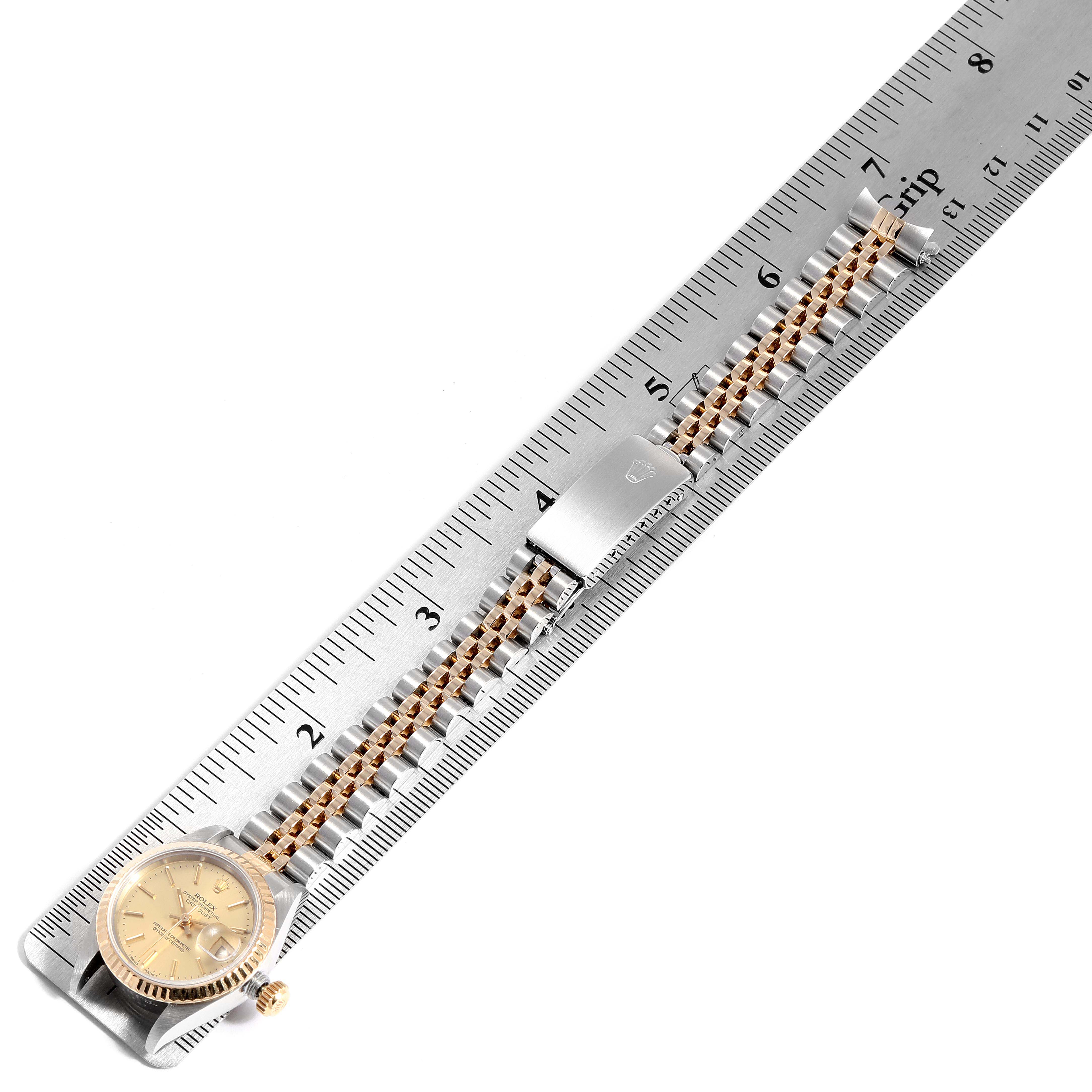The image shows the Rolex Datejust 69173 Women
s Steel and Gold (two tone) Champagne Dial 69173 Women
s Steel and Gold (two tone) Champagne Dial watch laid flat along a ruler, displaying its face, bracelet, and clasp.