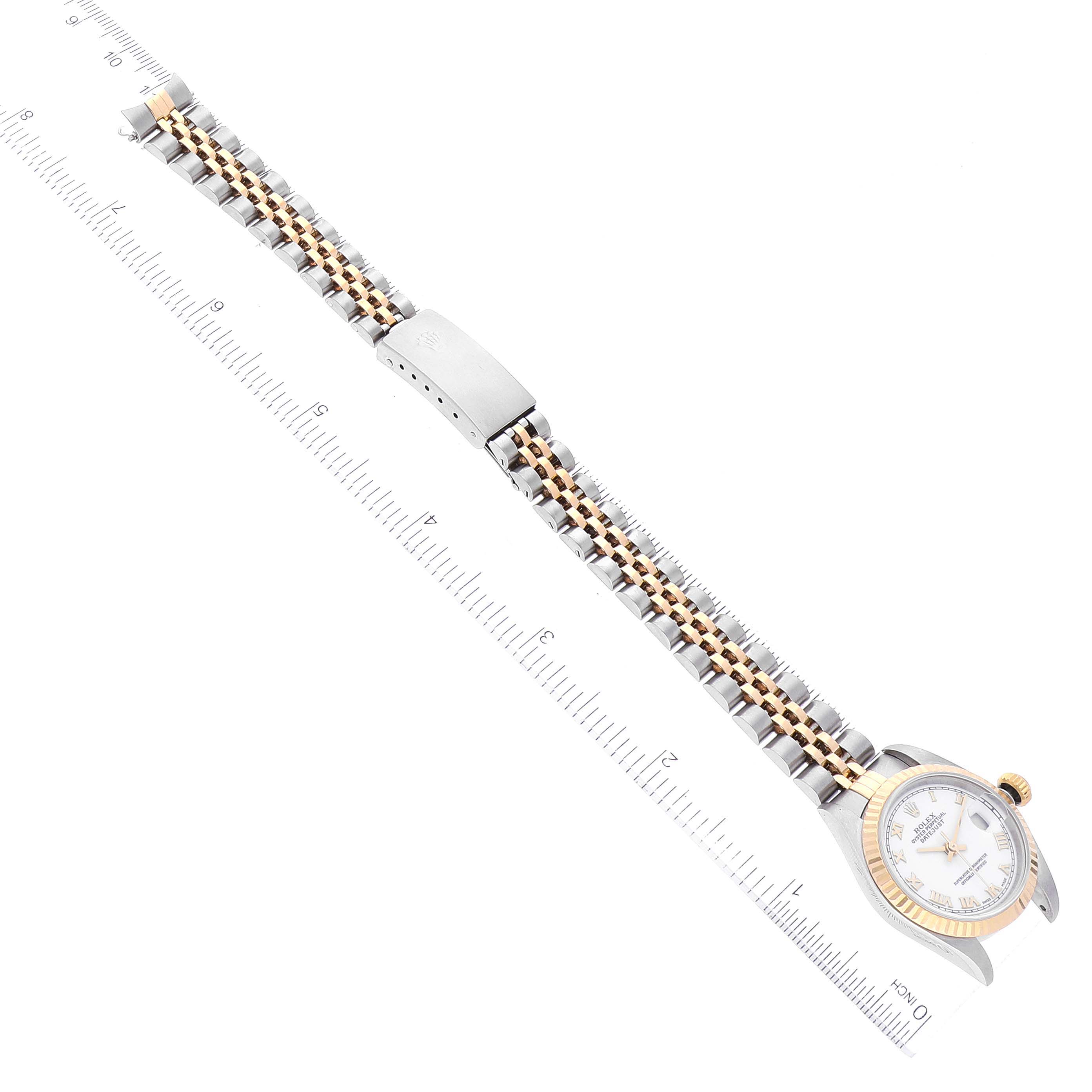 The Rolex Datejust 79173 Women's Steel and Gold (two tone) White Dial 79173 Women's Steel and Gold (two tone) White Dial watch is shown from a top-down angle, displaying the face, bezel, and full bracelet alongside a ruler for scale.