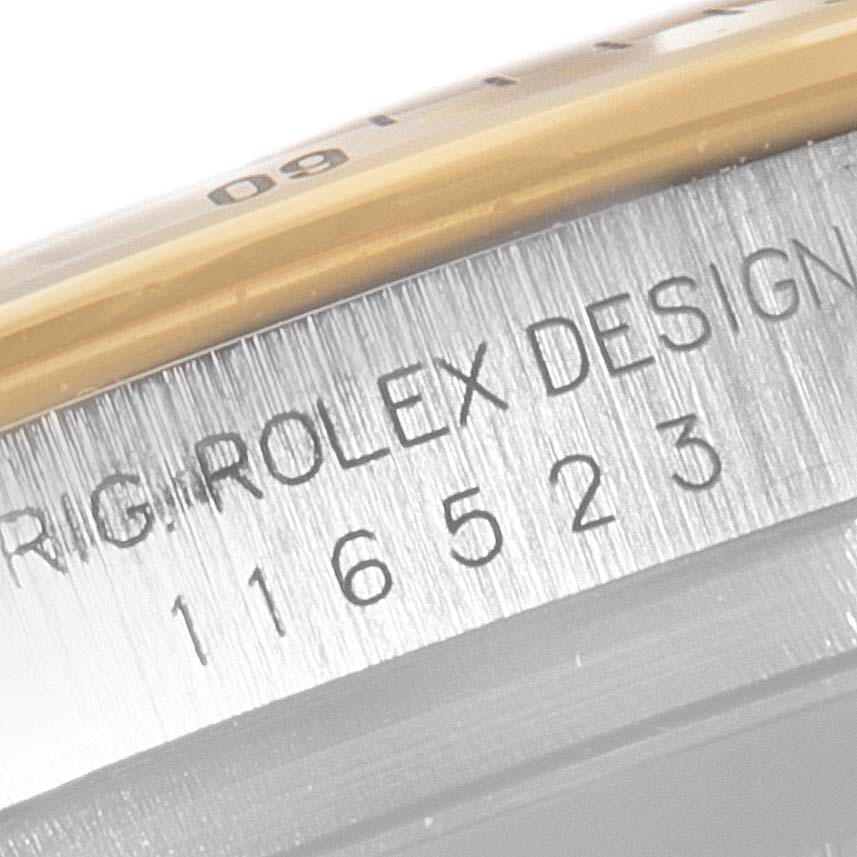 The image shows a close-up of the side engraving on a Rolex Daytona 116523 Men's Steel and Gold (two tone) Black Dial 116523 Men's Steel and Gold (two tone) Black Dial, displaying the model number "116523" and part of the bezel.