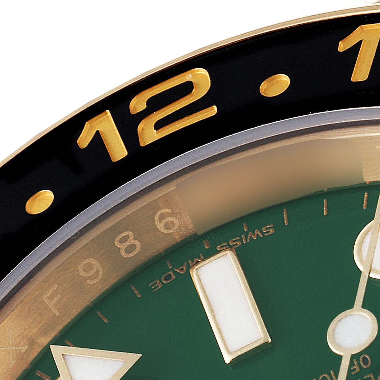 This close-up image shows the bezel and part of the dial of a Rolex GMT-Master 116718LN Men's Yellow Gold Green Dial 116718LN Men's Yellow Gold Green Dial watch.