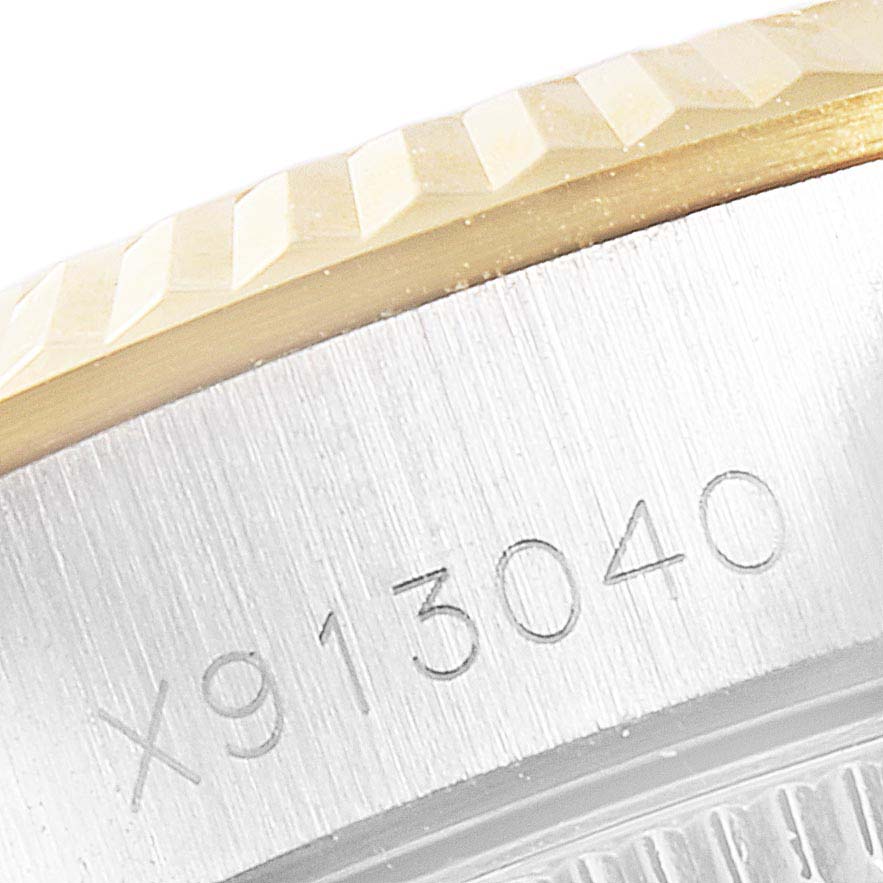 This image shows a close-up of the side of a Rolex Oyster Perpetual 67193 Women's Steel and Gold (two tone) Champagne Dial 67193 Women's Steel and Gold (two tone) Champagne Dial watch, focusing on the engraved serial number and bezel.