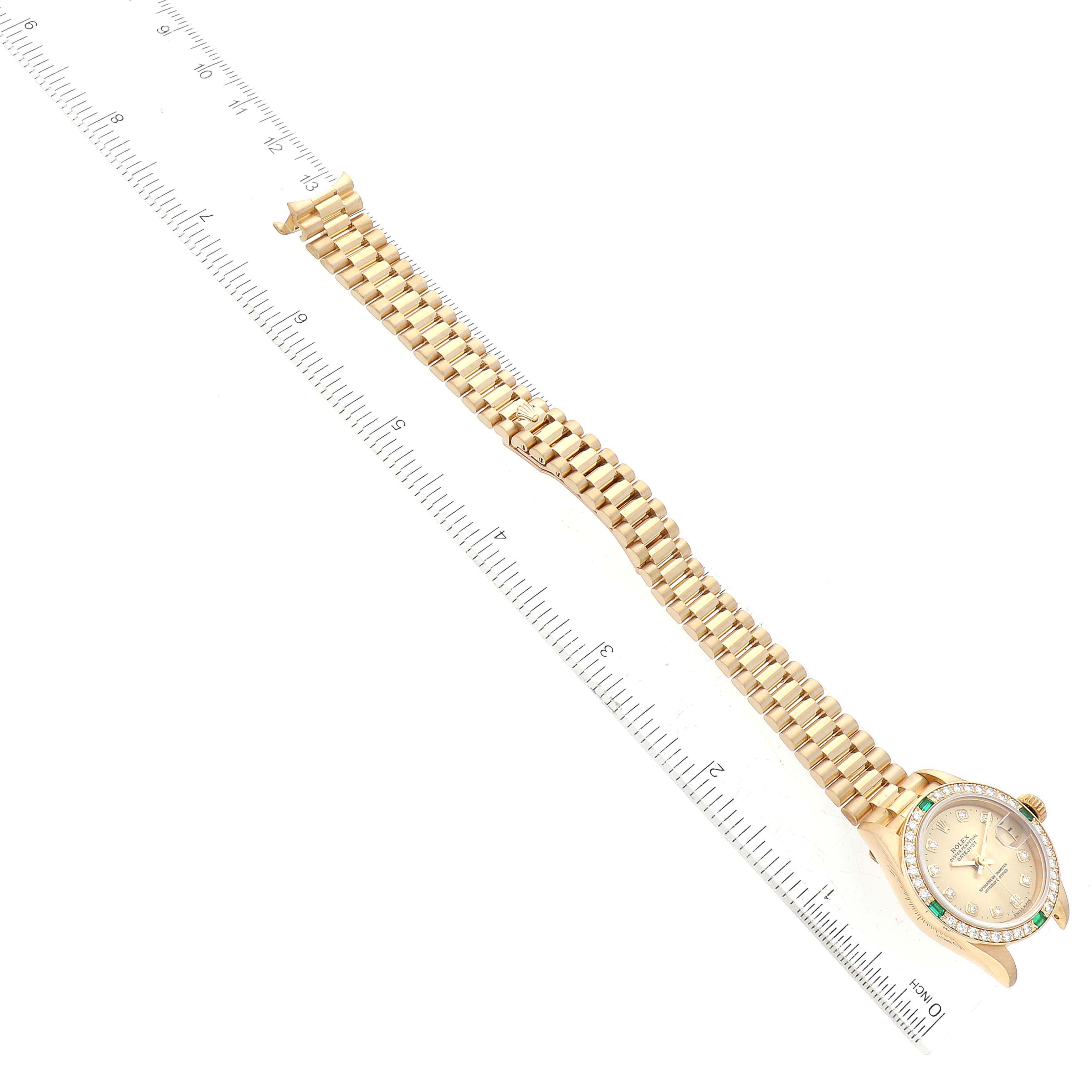 The Rolex President 69078 Women's Yellow Gold Champagne Dial 69078 Women's Yellow Gold Champagne Dial model watch is shown at a diagonal angle with its bracelet fully extended next to a ruler.