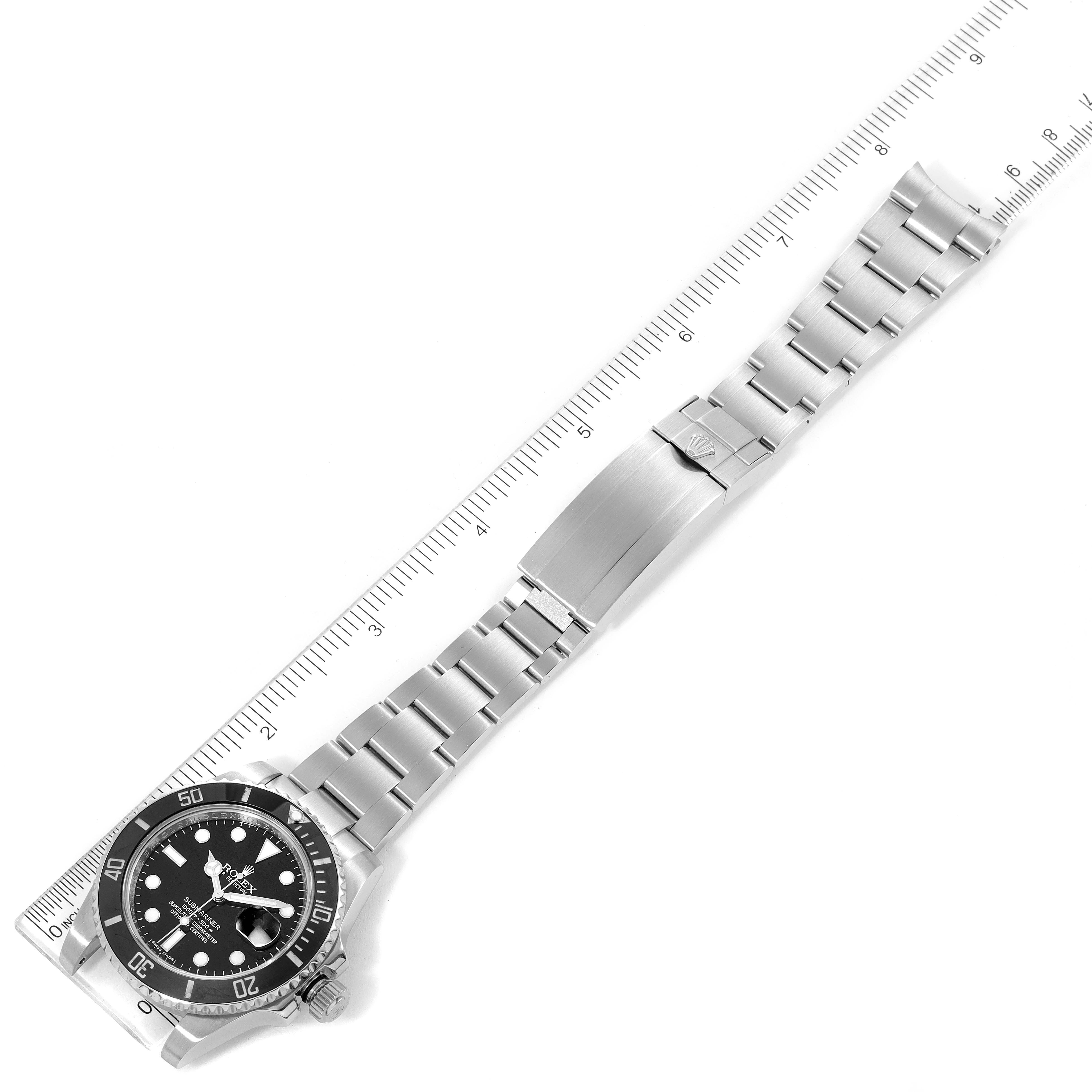 The image shows a top-down view of a Rolex Submariner 116610 Men's Stainless Steel Black Dial 116610 Men's Stainless Steel Black Dial watch, including its stainless steel bracelet and clasp with a measuring ruler alongside.