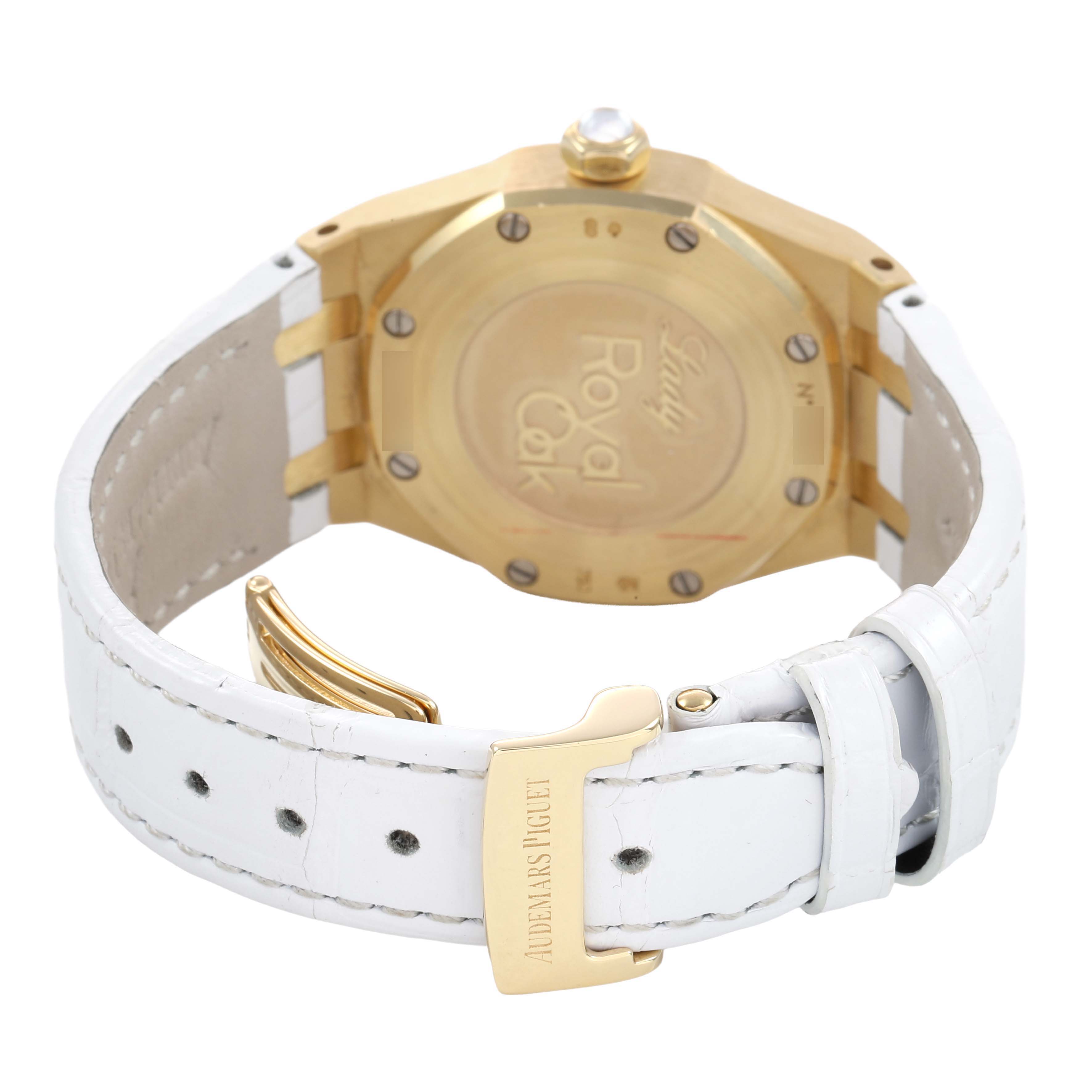 The image shows the back of a Royal Oak by Audemars Piguet, highlighting the gold case and white leather strap with a branded clasp.