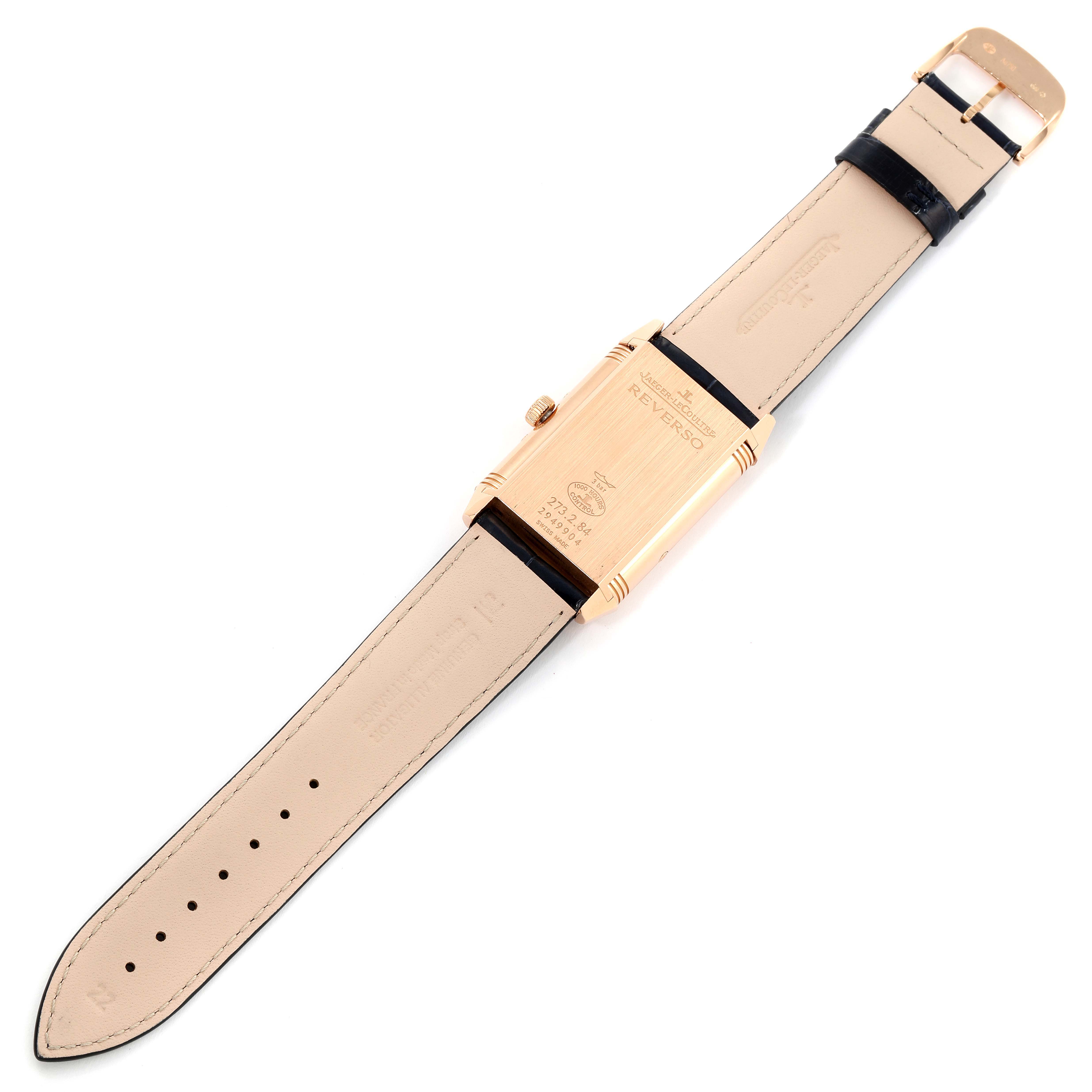 The image shows a Jaeger-LeCoultre Reverso watch from the back, displaying the case, crown, and straps.