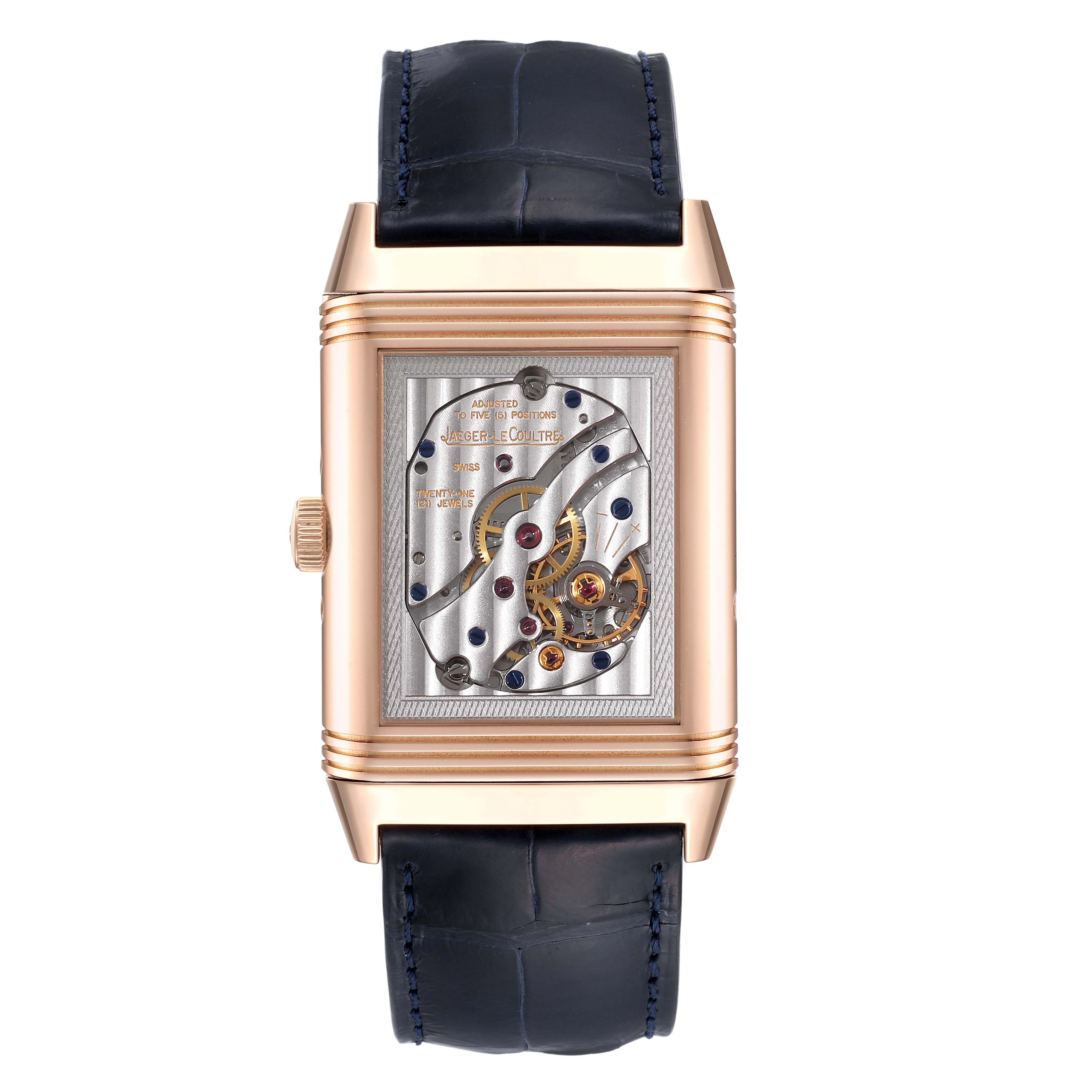 The image shows the back view of a Jaeger-LeCoultre Reverso watch, highlighting its mechanical movement and gold casing.